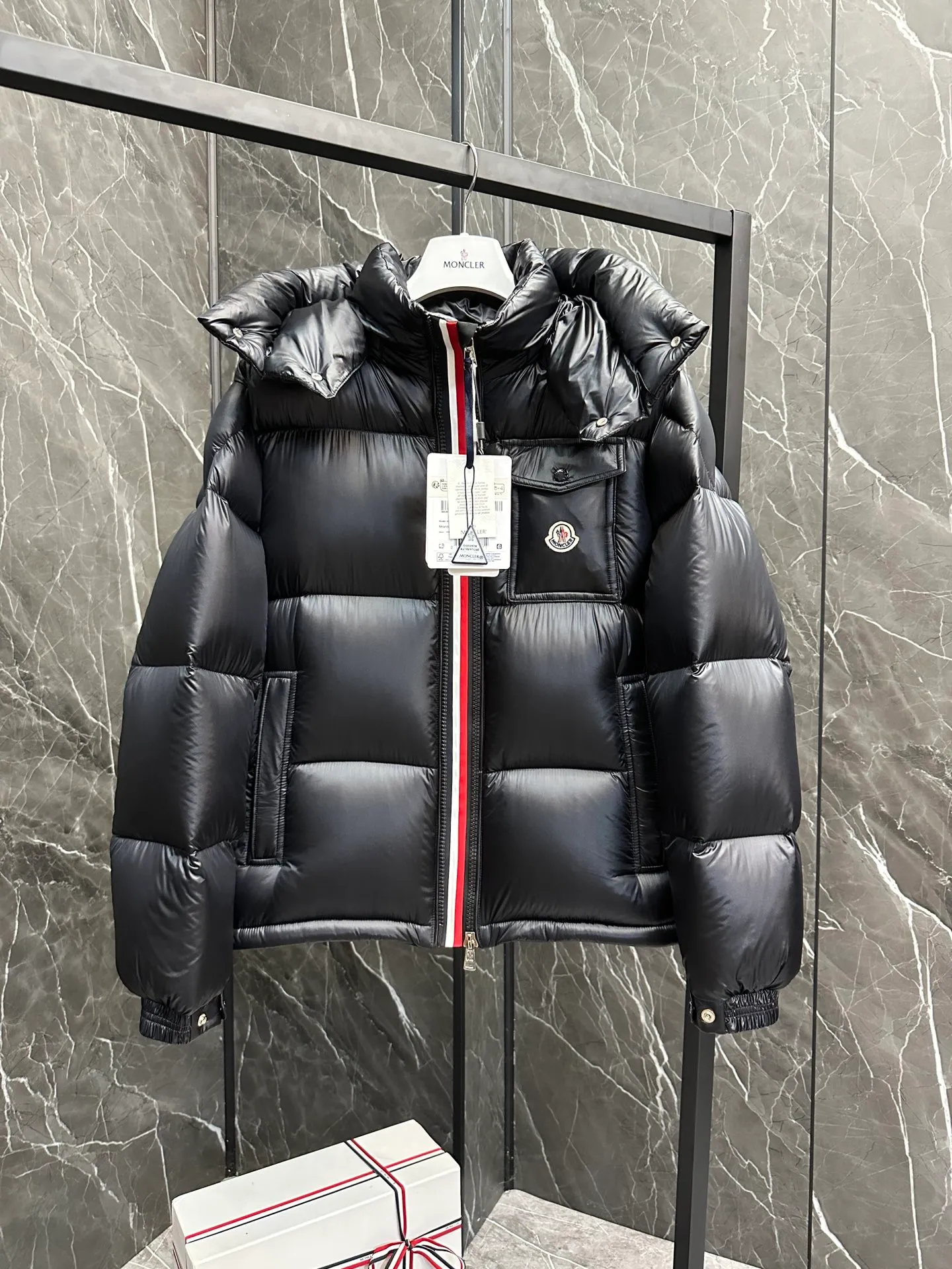 P740 ⬆️Moncler Montbeliard Short Men's Down Jacket Jacket Montbeliard Men's Short Down Jacket has warmth and protection functions, highlighting the fashionable Moncler aesthetic, and is a popular product. The Montbeliard down jacket is made from shiny patented nylon and features recognizable rectangular quilting. Featuring a hooded design and signature patch pocket at chest. Details •Made from nylon laqué fabric •Nylon laqué lining •Filled with down •Removable and adjustable hood with drawstring closure •Internal flap with webbing •Black pocket detail at lower end •Zipper closure •Snap-button closure at collar •Zipper pockets •Push-button closure at patch pockets •Adjustable cuffs •Adjustable elastic drawstring hem Size: 1-5 Couple's Black D9875067650