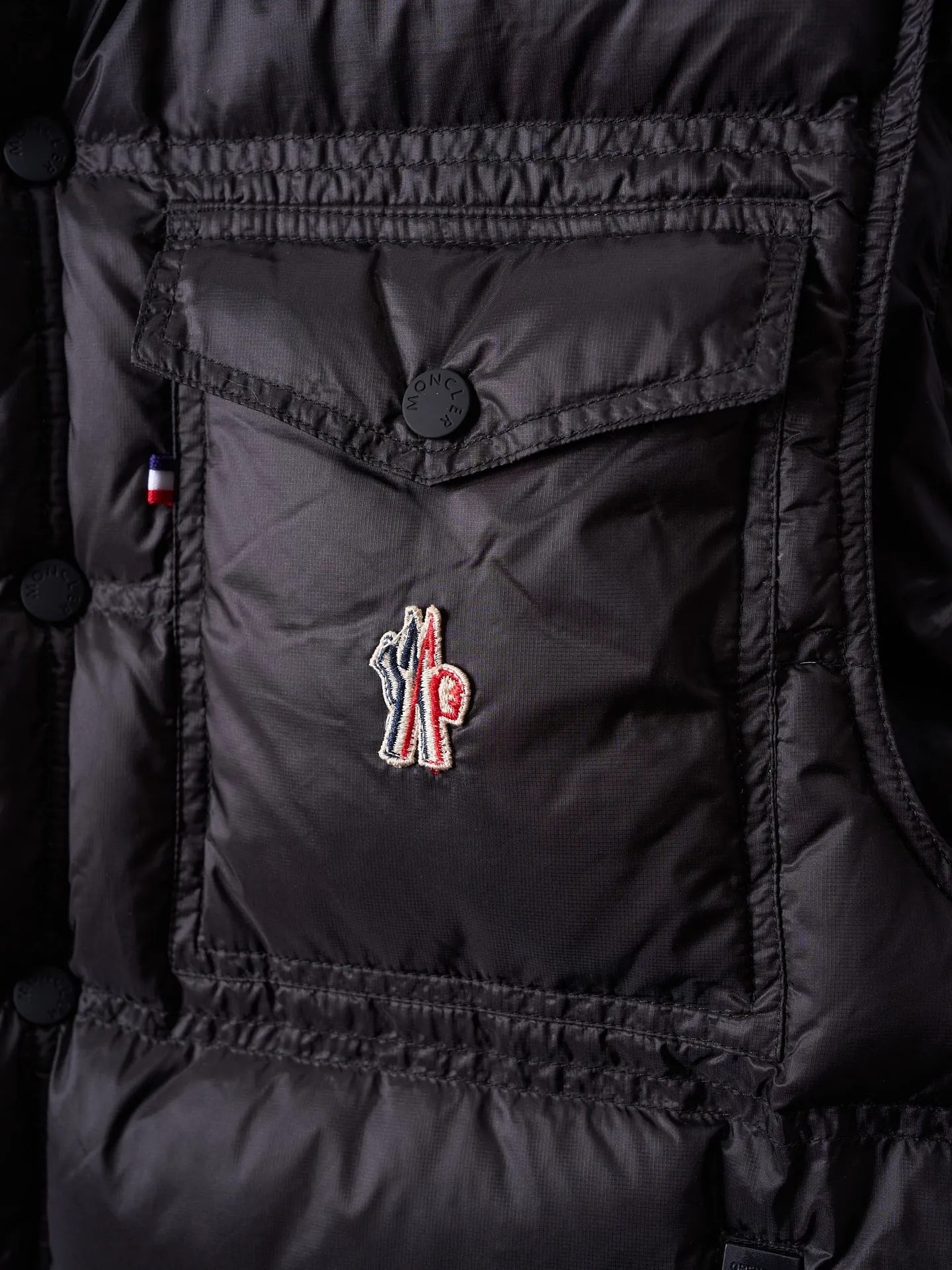 P680 Actual hanging auction] MONCLER/Mandow embroidered reflective logo stand-up collar down vest [Ready stock] 1 2 3 4 It is made of extremely fine nylon yarn and woven in a high-density way. The number of yarns per unit area is large, and the gaps between the yarns are very small, which can effectively block the penetration of cold wind. The fine weave keeps it lightweight and soft to the touch, physically restricting the lightweight down fibers from slipping through the gaps. Nylon fiber itself has good wear resistance and is not easy to snag, which significantly extends its service life and can easily cope with the needs of multiple scenarios.  The lining is made of high-density weaving of 100% polyester fiber, with a thickness of 0.08mm to avoid increasing the overall weight and making it smooth to wear. The high-density weaving structure forms a wind resistance layer to protect the thermal efficiency of the thermal layer from loss. It can withstand the expansion pressure of down and prevent deformation and damage after long-term use.  It uses 90 white duck down with a weight of 130g to ensure excellent thermal insulation performance. After strict screening and processing, the velvet is not easy to get drilled, ensuring durability.  Through the reflective cloth punching process, the logo is regularly arranged on the triangular reflective mark with dozens of small holes, which not only improves functionality but also enhances recognition and aesthetics.