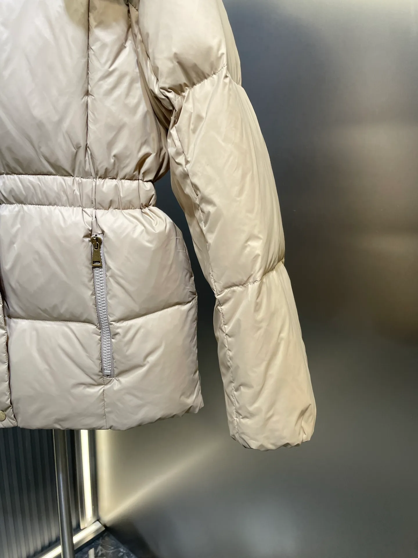 P910 MONCLER 25FW new autumn and winter product. Waisted black gold Agneux women's square quilted hooded short down jacket. The Agneux down jacket combines protective fabrics and exquisite textures. Short fit in functional nylon with a glossy satin finish. Paired with a nipped-in waist design, it outlines a feminine silhouette. Made of nylon Longue saison lining Filled with down Detachable and adjustable hood Zip and snap fastening Zippered pockets Elastic waist Black Apricot Sizes S M L