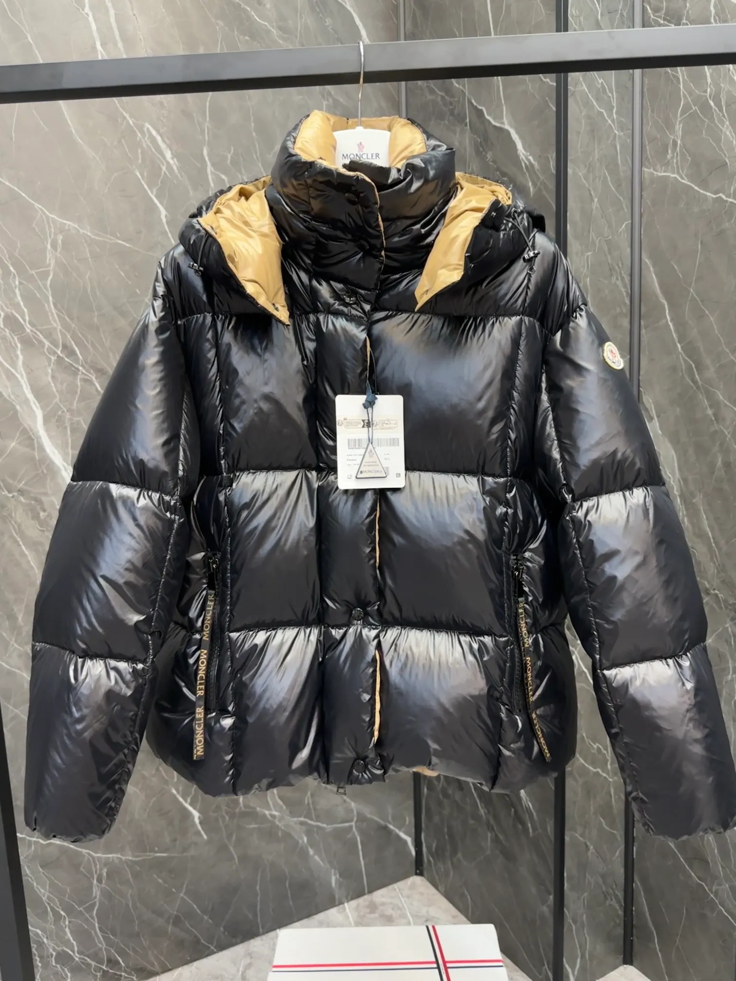 P720 Premium Down ⬆️ The Moncler Parana down jacket stands out with its shiny patented nylon fabric, featuring contrasting interior and exterior tones. The short design, the hood is detachable when the weather warms up, and the large drawstring draw inspiration from trendy brand logo fashion, embellished with Moncler letters.  •Made of patented nylon •Patented nylon lining •95 EU goose down filling •Removable hood •Contrast color lining •Zip and snap fastening •Zip pockets •Felt logo Size:0-3 Women's D9880046730