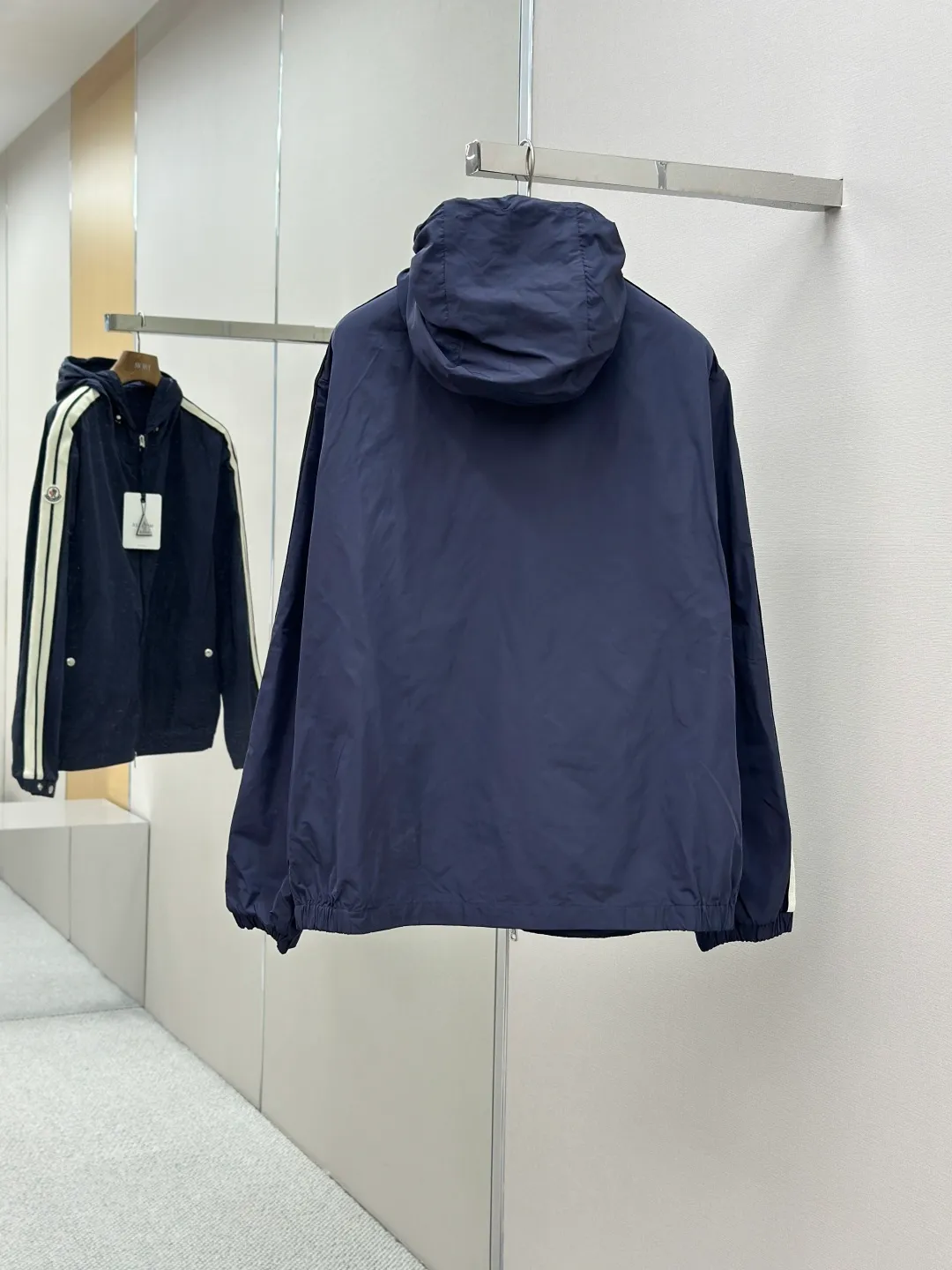 P560 MONCLER web-trimmed lightweight jacket Fabric selection: 100% polyester fiber is used to create a tough protective outer layer. It is known for its excellent tear resistance and wear resistance. It can quickly return to flatness during wearing and maintain the crisp and stylish appearance of the clothing for a long time. At the same time, it is not easy to deform after being washed for a long time.   Features: Two different colored decorative strips added to the center part of the sleeves. This design element can not only add visual highlights to clothing, making it more fashionable and unique. Craftsmanship: The webbing is precisely positioned along the cuffs to the seam of the collar and hat to ensure symmetry and overall smoothness. Before actual sewing, use very fine basting stitches for pre-fixing. This step is crucial to prevent the webbing from slipping, twisting, or wrinkling during sewing and ensuring that the final stitch is straight and perfect.  Accessories: Custom zipper puller, custom buttons with logo, custom hood drawstring elastic buckle SIZE: 1 2 3 4