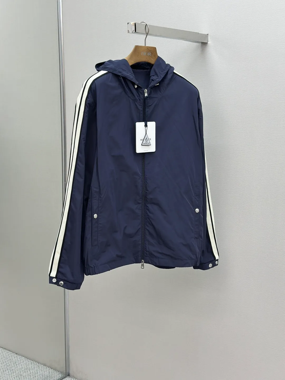 P560 MONCLER web-trimmed lightweight jacket Fabric selection: 100% polyester fiber is used to create a tough protective outer layer. It is known for its excellent tear resistance and wear resistance. It can quickly return to flatness during wearing and maintain the crisp and stylish appearance of the clothing for a long time. At the same time, it is not easy to deform after being washed for a long time.   Features: Two different colored decorative strips added to the center part of the sleeves. This design element can not only add visual highlights to clothing, making it more fashionable and unique. Craftsmanship: The webbing is precisely positioned along the cuffs to the seam of the collar and hat to ensure symmetry and overall smoothness. Before actual sewing, use very fine basting stitches for pre-fixing. This step is crucial to prevent the webbing from slipping, twisting, or wrinkling during sewing and ensuring that the final stitch is straight and perfect.  Accessories: Custom zipper puller, custom buttons with logo, custom hood drawstring elastic buckle SIZE: 1 2 3 4