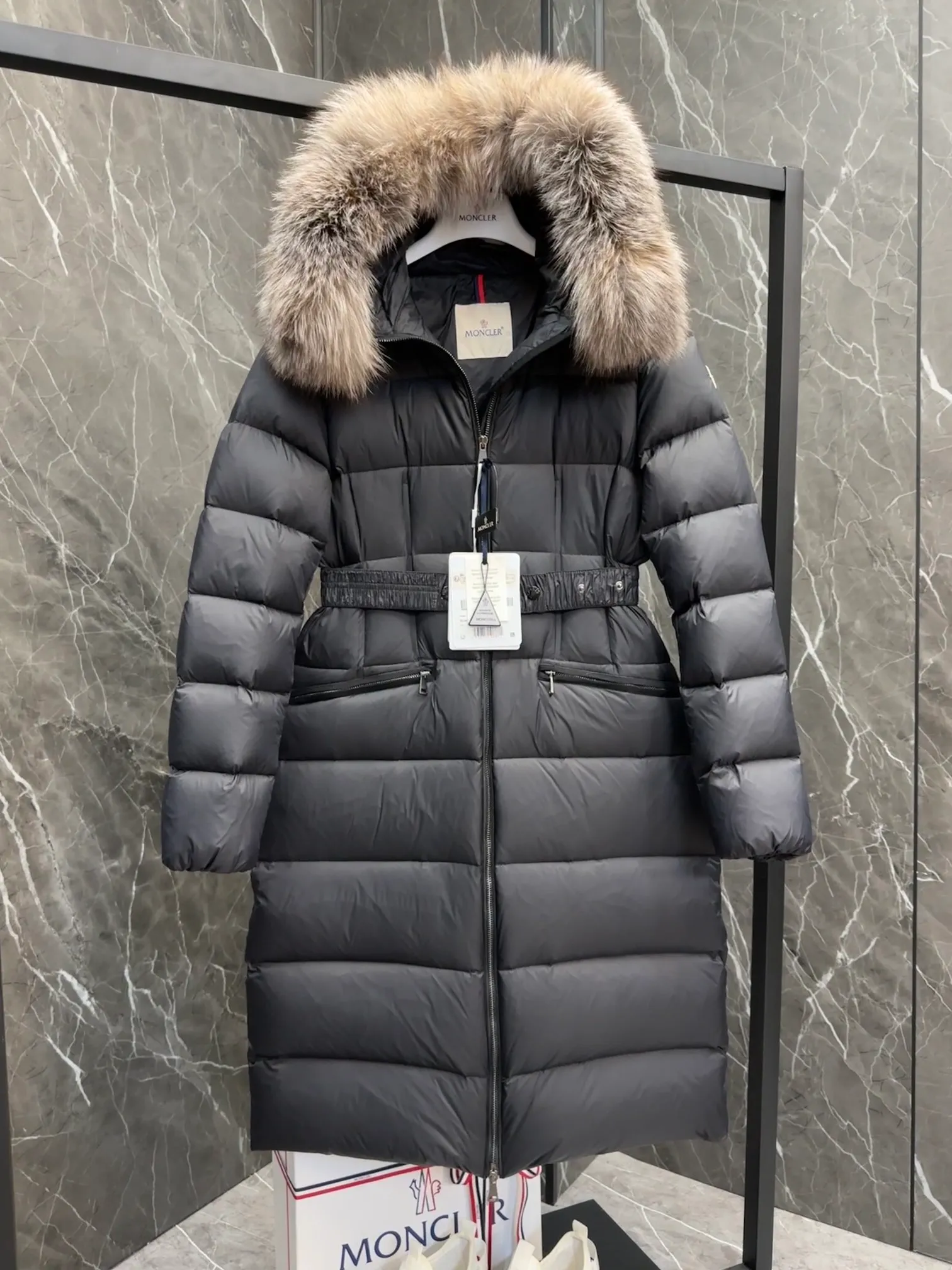 P1020 Moncler Boedic long down jacket for women. (Classic fox fur collar) adopts a whole fox fur collar imported from Finland. The Boedic long down jacket combines exquisite materials and attention to details. The timeless and elegant fashion design can provide you with a warm and caring wearing experience.  Boedic's long down jacket features a waist-cinching belt to accentuate its feminine silhouette for a stylish winter look. The cozy hood has rich fleece trim and is easily removable to suit your mood and weather conditions. Details • Made of lounge saison fabric • Longue saison lining • Filled with down • Hood with removable fox fur collar trim • Two-way zipper closure • Elastic waistband with snap button closure • Zippered pockets with grosgrain detail • Elastic cuffs Size : 1-4 .