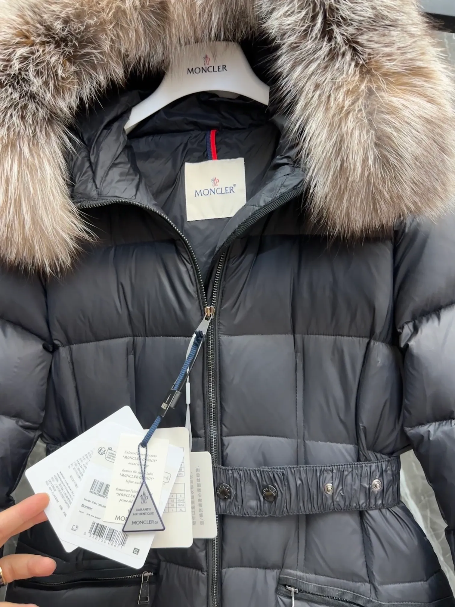 P1020 Moncler Boedic long down jacket for women. (Classic fox fur collar) adopts a whole fox fur collar imported from Finland. The Boedic long down jacket combines exquisite materials and attention to details. The timeless and elegant fashion design can provide you with a warm and caring wearing experience.  Boedic's long down jacket features a waist-cinching belt to accentuate its feminine silhouette for a stylish winter look. The cozy hood has rich fleece trim and is easily removable to suit your mood and weather conditions. Details • Made of lounge saison fabric • Longue saison lining • Filled with down • Hood with removable fox fur collar trim • Two-way zipper closure • Elastic waistband with snap button closure • Zippered pockets with grosgrain detail • Elastic cuffs Size : 1-4 .