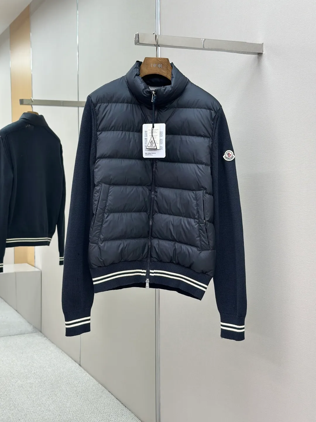 P830 Moncler Wool Splicing Fabric Selection: The front body fabric is made of 100% polyester fiber high-density weaving, with a thickness of 0.08mm to avoid increasing the overall weight and being smooth. The high-density weaving structure forms a wind resistance layer to protect the thermal efficiency of the thermal insulation layer from loss. At the same time, it can withstand the expansion pressure of down and prevent deformation and damage after long-term use.  The splicing design of the hood not only retains the warmth retention performance, but also incorporates the fashion elements, making the whole thing both practical and fashionable.  High-quality material: It is famous for its high-quality white duck down filling, with a filling capacity of 110g, and excellent warmth retention effect. At the same time, some are made of natural fiber materials such as wool and cashmere, which are soft, comfortable and skin-friendly.  The splicing process is exquisite to ensure comfortable wearing and not easy to get off-line or velvet.  High collar design: not only provides excellent thermal insulation effect, but also adds a unique sense of fashion, allowing the wearer to maintain style in the cold season.  Stripe decoration: The stripes on the cuffs and hem are like bright brushstrokes, embellished on the navy blue, injecting vitality and movement into the overall shape, making it more eye-catching.  Accessories: Customized zipper puller Customized badge Size: 1 2 3 4