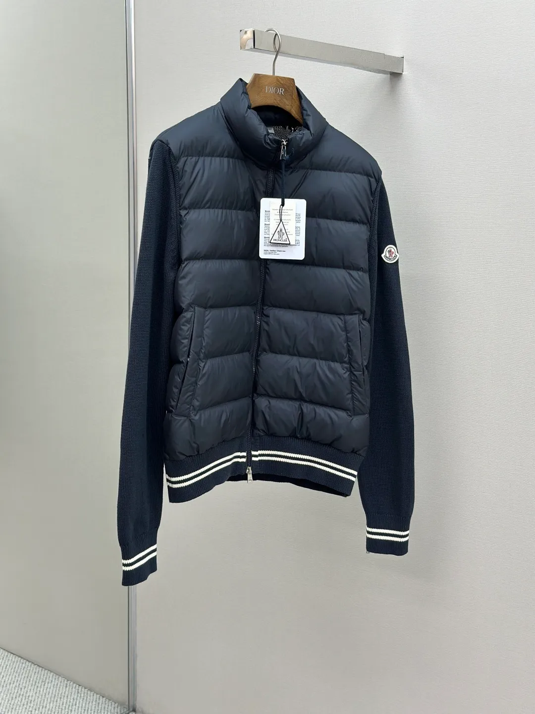 P830 Moncler Wool Splicing Fabric Selection: The front body fabric is made of 100% polyester fiber high-density weaving, with a thickness of 0.08mm to avoid increasing the overall weight and being smooth. The high-density weaving structure forms a wind resistance layer to protect the thermal efficiency of the thermal insulation layer from loss. At the same time, it can withstand the expansion pressure of down and prevent deformation and damage after long-term use.  The splicing design of the hood not only retains the warmth retention performance, but also incorporates the fashion elements, making the whole thing both practical and fashionable.  High-quality material: It is famous for its high-quality white duck down filling, with a filling capacity of 110g, and excellent warmth retention effect. At the same time, some are made of natural fiber materials such as wool and cashmere, which are soft, comfortable and skin-friendly.  The splicing process is exquisite to ensure comfortable wearing and not easy to get off-line or velvet.  High collar design: not only provides excellent thermal insulation effect, but also adds a unique sense of fashion, allowing the wearer to maintain style in the cold season.  Stripe decoration: The stripes on the cuffs and hem are like bright brushstrokes, embellished on the navy blue, injecting vitality and movement into the overall shape, making it more eye-catching.  Accessories: Customized zipper puller Customized badge Size: 1 2 3 4