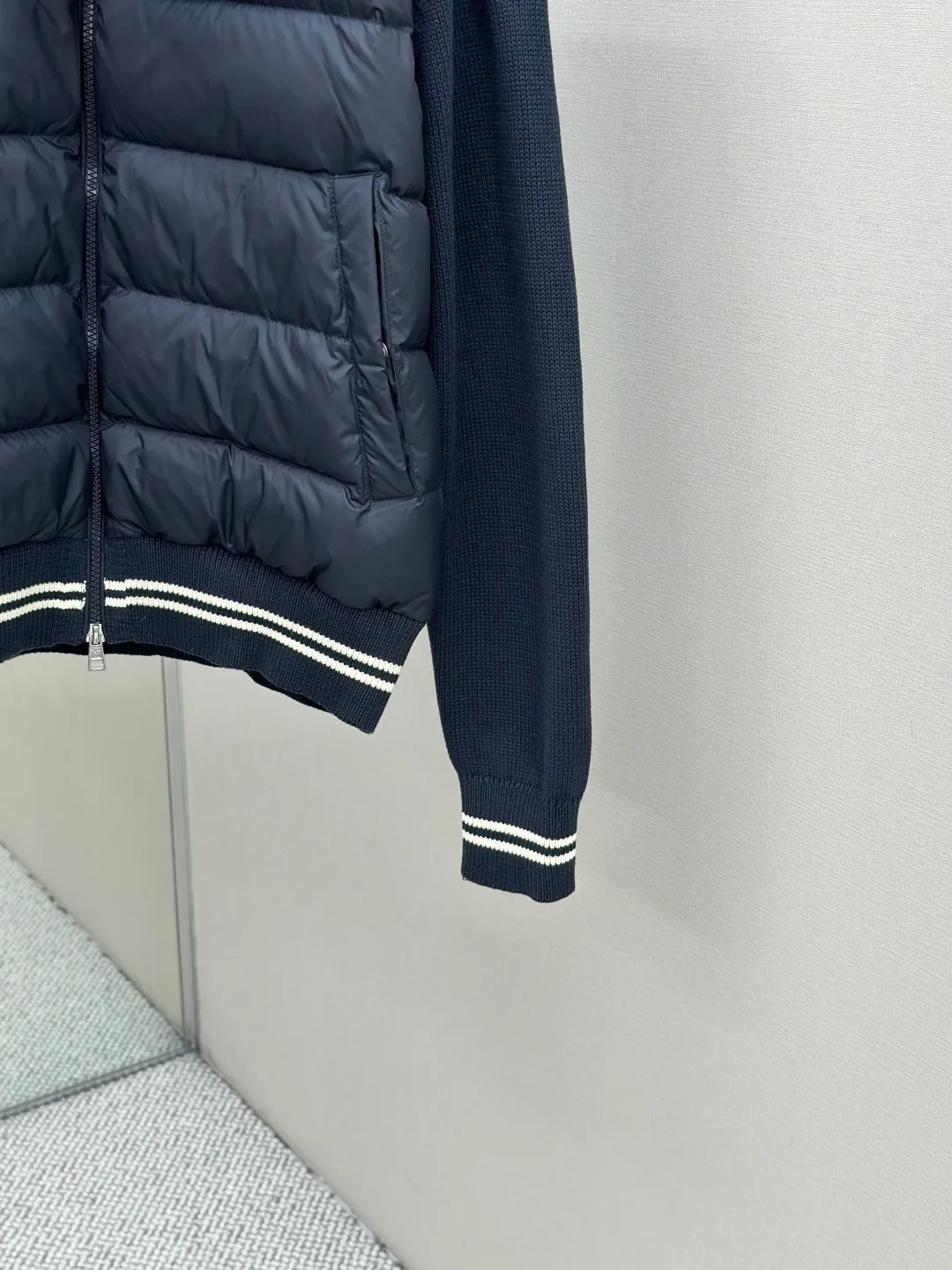P830 Moncler Wool Splicing Fabric Selection: The front body fabric is made of 100% polyester fiber high-density weaving, with a thickness of 0.08mm to avoid increasing the overall weight and being smooth. The high-density weaving structure forms a wind resistance layer to protect the thermal efficiency of the thermal insulation layer from loss. At the same time, it can withstand the expansion pressure of down and prevent deformation and damage after long-term use.  The splicing design of the hood not only retains the warmth retention performance, but also incorporates the fashion elements, making the whole thing both practical and fashionable.  High-quality material: It is famous for its high-quality white duck down filling, with a filling capacity of 110g, and excellent warmth retention effect. At the same time, some are made of natural fiber materials such as wool and cashmere, which are soft, comfortable and skin-friendly.  The splicing process is exquisite to ensure comfortable wearing and not easy to get off-line or velvet.  High collar design: not only provides excellent thermal insulation effect, but also adds a unique sense of fashion, allowing the wearer to maintain style in the cold season.  Stripe decoration: The stripes on the cuffs and hem are like bright brushstrokes, embellished on the navy blue, injecting vitality and movement into the overall shape, making it more eye-catching.  Accessories: Customized zipper puller Customized badge Size: 1 2 3 4