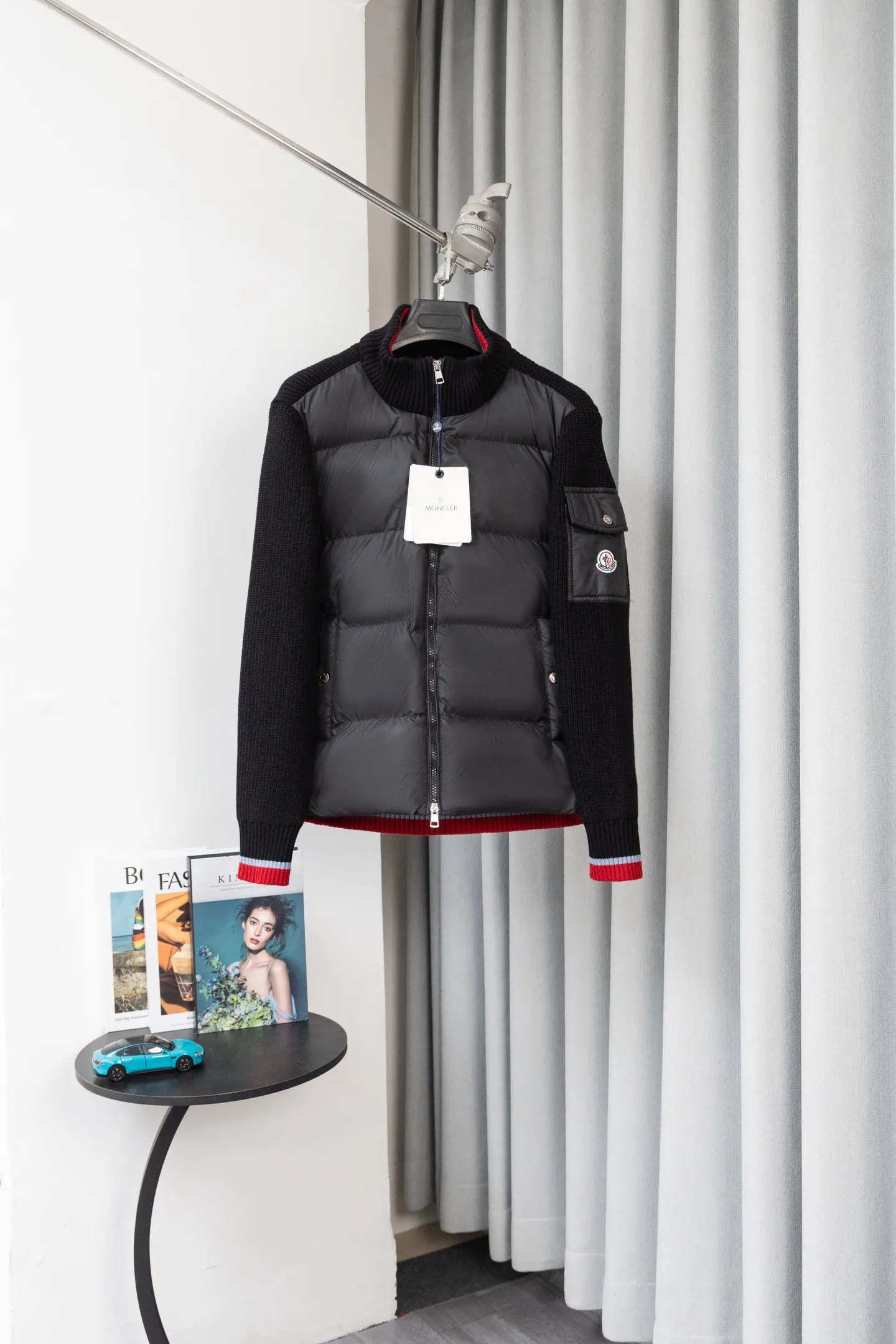 P560 Style number: M046 This is a knitted patchwork down jacket from Moncler. It combines the brand's high-end outdoor genes and fashion design. It is a luxurious item with both warmth and style in autumn and winter. Design highlights: Material splicing: Pure wool knitted sleeves are spliced ​​with a down front filled with 90 white duck down. The knitted part is soft and breathable, and the down part is fluffy and warm, achieving a dual fusion of style and function.  Detailed logo: The iconic Moncler badge pocket on the left arm is a classic embodiment of brand recognition; the stand-up collar design with a two-way zipper not only improves warmth, but also strengthens the neat styling.  Color embellishment: The contrasting red and blue stripes on the cuffs and hem inject vitality into the overall black tone, adding a retro college style charm. Craftsmanship and Quality: The down filling follows the European standard 90 down standard, with excellent fluffiness and down filling, with almost no stiff feeling. At the same time, it adopts the "line first and then separate down filling" process. The four-layer liner effectively prevents down from being drilled, and can maintain warmth even after long-term wear.  The knitted part is made of high-quality wool, which has a delicate touch and is not easily deformed. The splicing process with the down fabric is rigorous, showing a high-end texture level.  Style and Wearing This down jacket is based on the classic college style. The slim straight version can modify the body line and can be easily adapted to a variety of styles: it can be paired with jeans and casual shoes for a casual look on a daily basis. It can also be upgraded to an urban light luxury style by layering it with a turtleneck sweater inside and a suit outside. It is a key item in the winter wardrobe that is both practical and fashionable. Color: black, navy blue, sizes S-XL