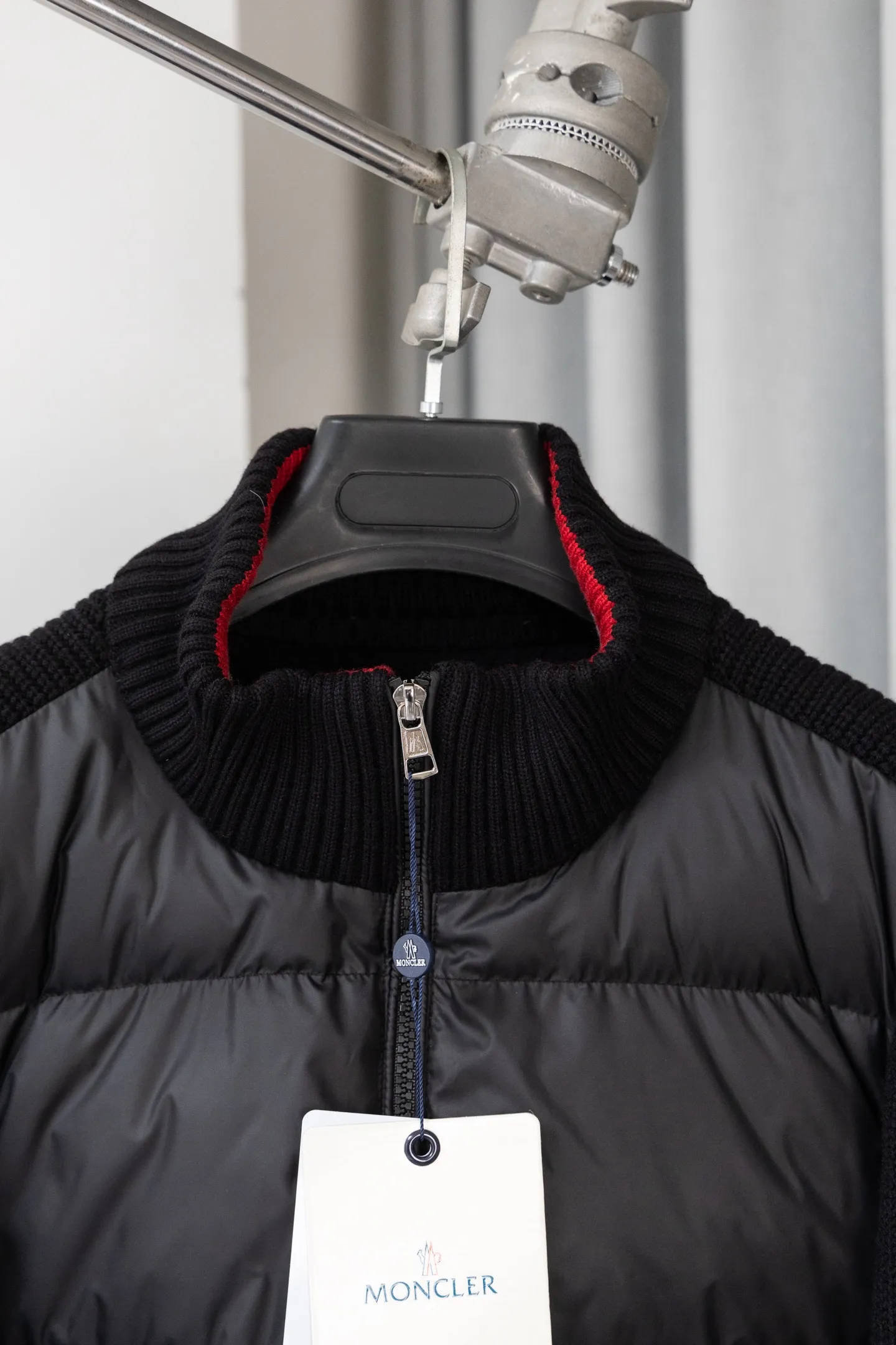 P560 Style number: M046 This is a knitted patchwork down jacket from Moncler. It combines the brand's high-end outdoor genes and fashion design. It is a luxurious item with both warmth and style in autumn and winter. Design highlights: Material splicing: Pure wool knitted sleeves are spliced ​​with a down front filled with 90 white duck down. The knitted part is soft and breathable, and the down part is fluffy and warm, achieving a dual fusion of style and function.  Detailed logo: The iconic Moncler badge pocket on the left arm is a classic embodiment of brand recognition; the stand-up collar design with a two-way zipper not only improves warmth, but also strengthens the neat styling.  Color embellishment: The contrasting red and blue stripes on the cuffs and hem inject vitality into the overall black tone, adding a retro college style charm. Craftsmanship and Quality: The down filling follows the European standard 90 down standard, with excellent fluffiness and down filling, with almost no stiff feeling. At the same time, it adopts the "line first and then separate down filling" process. The four-layer liner effectively prevents down from being drilled, and can maintain warmth even after long-term wear.  The knitted part is made of high-quality wool, which has a delicate touch and is not easily deformed. The splicing process with the down fabric is rigorous, showing a high-end texture level.  Style and Wearing This down jacket is based on the classic college style. The slim straight version can modify the body line and can be easily adapted to a variety of styles: it can be paired with jeans and casual shoes for a casual look on a daily basis. It can also be upgraded to an urban light luxury style by layering it with a turtleneck sweater inside and a suit outside. It is a key item in the winter wardrobe that is both practical and fashionable. Color: black, navy blue, sizes S-XL