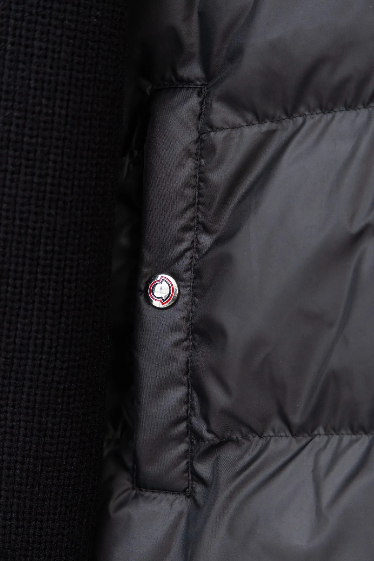 P560 Style number: M046 This is a knitted patchwork down jacket from Moncler. It combines the brand's high-end outdoor genes and fashion design. It is a luxurious item with both warmth and style in autumn and winter. Design highlights: Material splicing: Pure wool knitted sleeves are spliced ​​with a down front filled with 90 white duck down. The knitted part is soft and breathable, and the down part is fluffy and warm, achieving a dual fusion of style and function.  Detailed logo: The iconic Moncler badge pocket on the left arm is a classic embodiment of brand recognition; the stand-up collar design with a two-way zipper not only improves warmth, but also strengthens the neat styling.  Color embellishment: The contrasting red and blue stripes on the cuffs and hem inject vitality into the overall black tone, adding a retro college style charm. Craftsmanship and Quality: The down filling follows the European standard 90 down standard, with excellent fluffiness and down filling, with almost no stiff feeling. At the same time, it adopts the "line first and then separate down filling" process. The four-layer liner effectively prevents down from being drilled, and can maintain warmth even after long-term wear.  The knitted part is made of high-quality wool, which has a delicate touch and is not easily deformed. The splicing process with the down fabric is rigorous, showing a high-end texture level.  Style and Wearing This down jacket is based on the classic college style. The slim straight version can modify the body line and can be easily adapted to a variety of styles: it can be paired with jeans and casual shoes for a casual look on a daily basis. It can also be upgraded to an urban light luxury style by layering it with a turtleneck sweater inside and a suit outside. It is a key item in the winter wardrobe that is both practical and fashionable. Color: black, navy blue, sizes S-XL