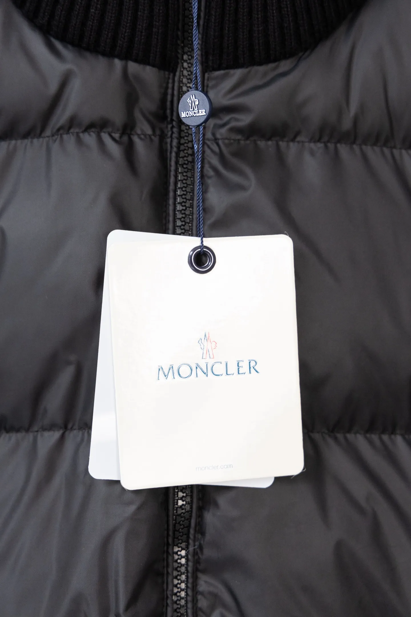 P560 Style number: M046 This is a knitted patchwork down jacket from Moncler. It combines the brand's high-end outdoor genes and fashion design. It is a luxurious item with both warmth and style in autumn and winter. Design highlights: Material splicing: Pure wool knitted sleeves are spliced ​​with a down front filled with 90 white duck down. The knitted part is soft and breathable, and the down part is fluffy and warm, achieving a dual fusion of style and function.  Detailed logo: The iconic Moncler badge pocket on the left arm is a classic embodiment of brand recognition; the stand-up collar design with a two-way zipper not only improves warmth, but also strengthens the neat styling.  Color embellishment: The contrasting red and blue stripes on the cuffs and hem inject vitality into the overall black tone, adding a retro college style charm. Craftsmanship and Quality: The down filling follows the European standard 90 down standard, with excellent fluffiness and down filling, with almost no stiff feeling. At the same time, it adopts the "line first and then separate down filling" process. The four-layer liner effectively prevents down from being drilled, and can maintain warmth even after long-term wear.  The knitted part is made of high-quality wool, which has a delicate touch and is not easily deformed. The splicing process with the down fabric is rigorous, showing a high-end texture level.  Style and Wearing This down jacket is based on the classic college style. The slim straight version can modify the body line and can be easily adapted to a variety of styles: it can be paired with jeans and casual shoes for a casual look on a daily basis. It can also be upgraded to an urban light luxury style by layering it with a turtleneck sweater inside and a suit outside. It is a key item in the winter wardrobe that is both practical and fashionable. Color: black, navy blue, sizes S-XL