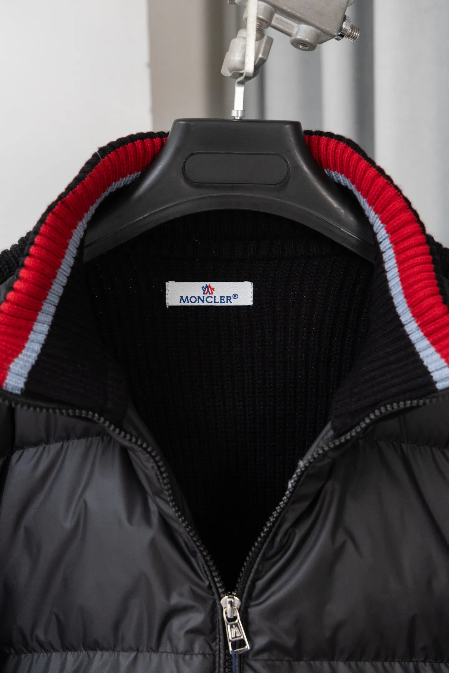 P560 Style number: M046 This is a knitted patchwork down jacket from Moncler. It combines the brand's high-end outdoor genes and fashion design. It is a luxurious item with both warmth and style in autumn and winter. Design highlights: Material splicing: Pure wool knitted sleeves are spliced ​​with a down front filled with 90 white duck down. The knitted part is soft and breathable, and the down part is fluffy and warm, achieving a dual fusion of style and function.  Detailed logo: The iconic Moncler badge pocket on the left arm is a classic embodiment of brand recognition; the stand-up collar design with a two-way zipper not only improves warmth, but also strengthens the neat styling.  Color embellishment: The contrasting red and blue stripes on the cuffs and hem inject vitality into the overall black tone, adding a retro college style charm. Craftsmanship and Quality: The down filling follows the European standard 90 down standard, with excellent fluffiness and down filling, with almost no stiff feeling. At the same time, it adopts the "line first and then separate down filling" process. The four-layer liner effectively prevents down from being drilled, and can maintain warmth even after long-term wear.  The knitted part is made of high-quality wool, which has a delicate touch and is not easily deformed. The splicing process with the down fabric is rigorous, showing a high-end texture level.  Style and Wearing This down jacket is based on the classic college style. The slim straight version can modify the body line and can be easily adapted to a variety of styles: it can be paired with jeans and casual shoes for a casual look on a daily basis. It can also be upgraded to an urban light luxury style by layering it with a turtleneck sweater inside and a suit outside. It is a key item in the winter wardrobe that is both practical and fashionable. Color: black, navy blue, sizes S-XL