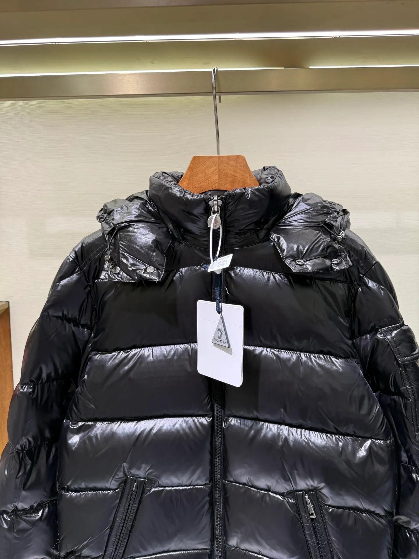 P1180 Moncler Maya Men's Men's Short Down Jacket The Moncler Maya men's down jacket is made of shiny patented nylon with signature rectangular quilting, which is a model of Moncler style. A classic cropped design that transcends seasons and styles, it features a statement silhouette, removable hood and adjustable hem. The sleeves are embellished with classic patch pockets, showcasing the brand's signature style.  Fabric: 100% nylon, 90% white goose down Craftsmanship: Made of lacquered nylon, lacquered nylon lining filled with down, rectangular quilting, detachable hood with snaps that can be adjusted by drawstring, two-way zip fly, external and internal zippered pockets, adjustable elastic cuffs with snaps, hood with drawstring, sleeves with flap patch pockets, sleeves decorated with Moncler felt trademark.  Size: 123456 0548000