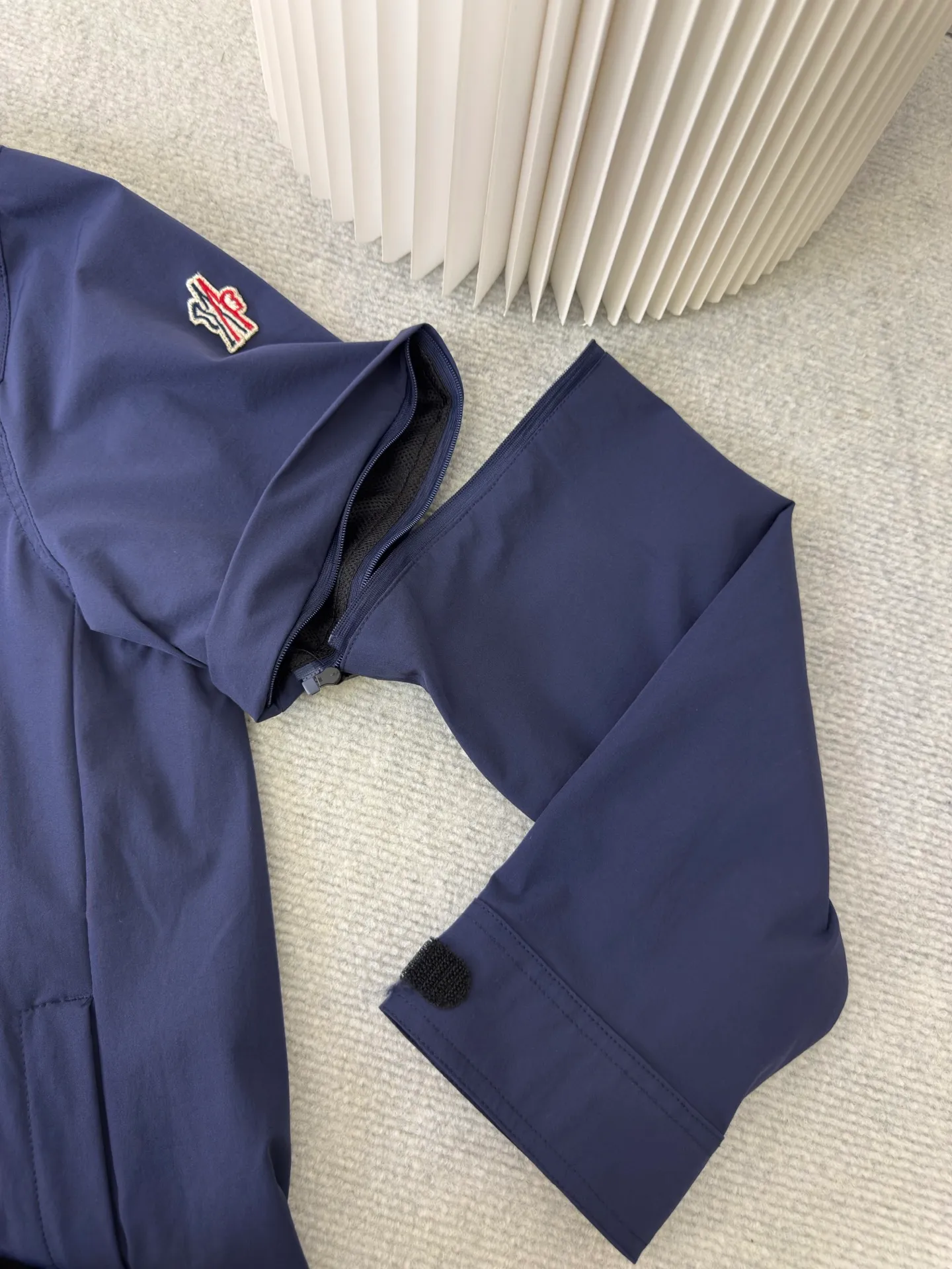 P640 Moncler Grenoble Functional Outdoor Jacket Custom-dyed double-stretch mercerized poplin Custom-dyed soft-mesh pongee Excellent texture Comfortable and close to the skin Dark green inspired by plant texture The color is taken from sage leaves soaked in morning dew Precision narrative of functional pocket system Balance of function and aesthetics The iconic Moncler logo appears on the sleeves, fully recognizable The triangular logo of the same color is hidden in the fabric texture like a mark in the undercurrent of the deep sea Extremely hidden and visible. The detachable sleeve design allows for diversified outfits. You can switch styles at will. Feel free and elegant. Show your dignity. Balance outdoor practicality and urban aesthetics. Lead the fashion. Adopt three-in-one process. Give priority to evenly coating the glue on the surface of the substrate that needs to be composited. Then dry and solidify. Then laminate the substrate with the adhesive film and the non-woven fabric. Then cool and solidify. Then composite the filter non-woven fabric. The workmanship is cumbersome and complex. Time-consuming and labor-intensive. Embossed composite technology Through computer scanning, ensure that the imprint size and shape are consistent with the original. Then use special glue as an adhesive to combine and then solidify to achieve complete dryness and the best bonding effect. Use CNC laser burning and cutting based on the high-energy characteristics of the laser. Precisely control the movement path of the laser beam with a laser generator to achieve precise cutting of the shape of the piece. Template machine bag opening. The preset template guides the position, shape and size of the bag opening. The accuracy ensures the quality of the bag opening effect. Uses infrared special machine to fasten the position more accurately. Strong and sturdy, loose fit, detachable sleeve splicing, style can be switched at will Size: 1 2 3 4