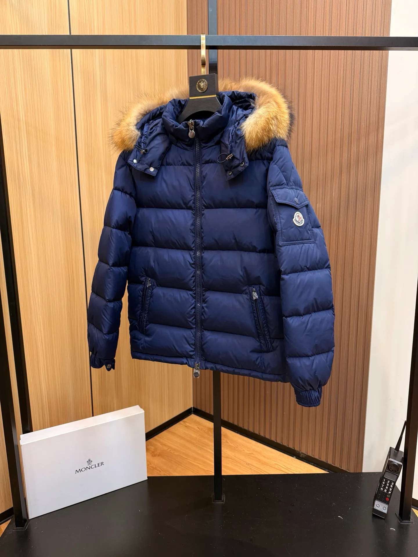 P1040 Moncler Mayaf short men's down jacket. The hood is removable. The fur collar is removable. Based on Maya, a removable fur collar is added. The Mayaf men's hooded down jacket is made of functional nylon fabric, and the hood is equipped with removable synthetic material trim.  The Mayaf short down jacket is a reinterpretation of the classic Moncler Maya style in an instantly recognizable silhouette, with a removable hood and adjustable hem. Made from functional fabric with removable synthetic trim on the hood. The sleeves are embellished with classic patch pockets, reflecting the brand's signature style. Details •Made from functional fabric •Technical fabric lining •Down-filled •Push-stud collar •Detachable hood with removable synthetic trim •Zip closure •Zip pockets •Patch pockets with press-stud •Adjustable elastic cuffs •Adjustable drawstring hem
