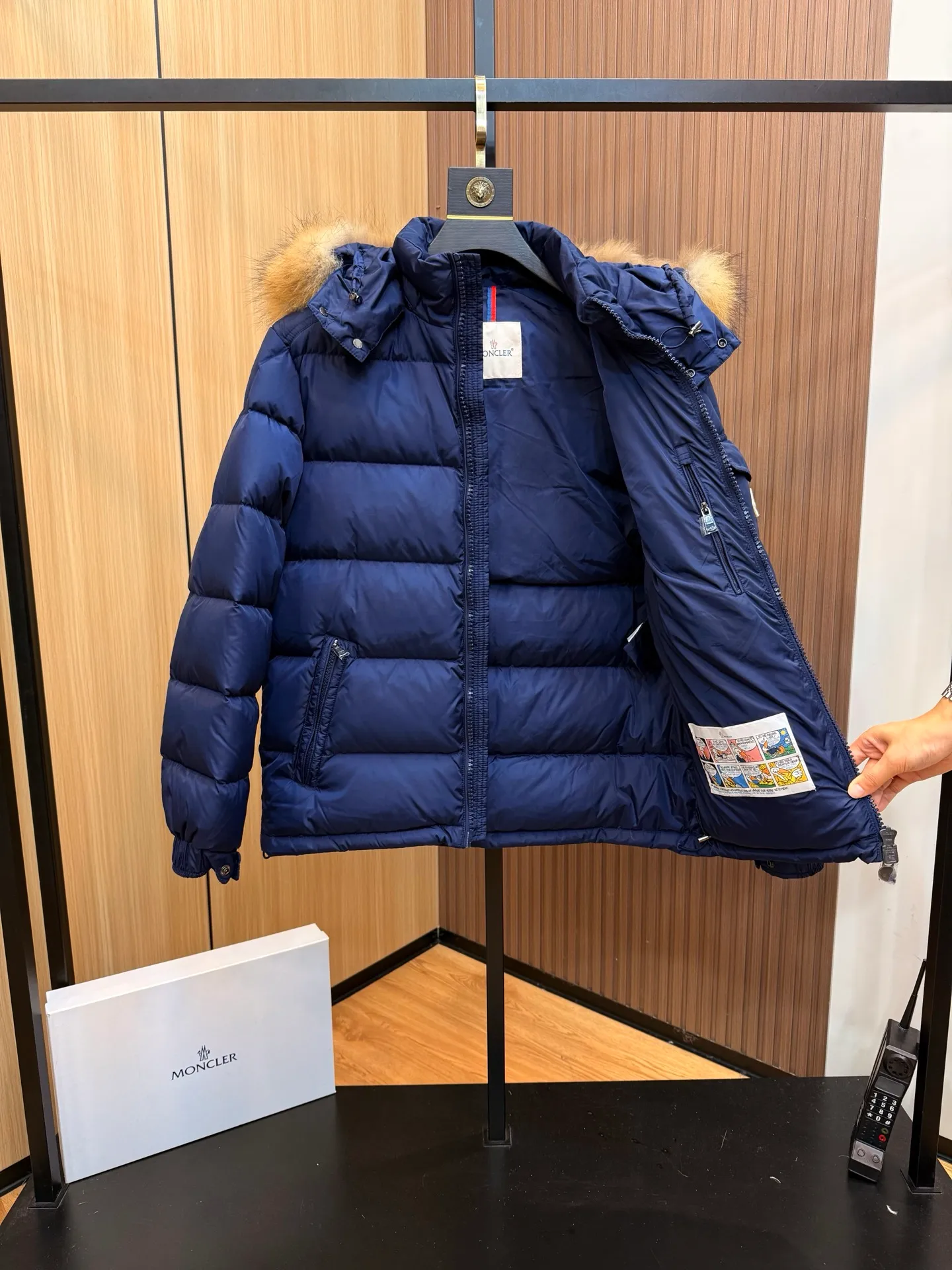 P1040 Moncler Mayaf short men's down jacket. The hood is removable. The fur collar is removable. Based on Maya, a removable fur collar is added. The Mayaf men's hooded down jacket is made of functional nylon fabric, and the hood is equipped with removable synthetic material trim.  The Mayaf short down jacket is a reinterpretation of the classic Moncler Maya style in an instantly recognizable silhouette, with a removable hood and adjustable hem. Made from functional fabric with removable synthetic trim on the hood. The sleeves are embellished with classic patch pockets, reflecting the brand's signature style. Details •Made from functional fabric •Technical fabric lining •Down-filled •Push-stud collar •Detachable hood with removable synthetic trim •Zip closure •Zip pockets •Patch pockets with press-stud •Adjustable elastic cuffs •Adjustable drawstring hem