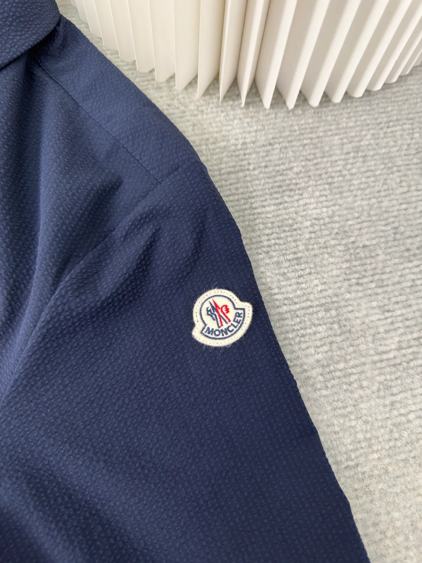 P450 MONCLER Puff Wrinkle Shirt Jacket. Authentic version - physical counter - top luxury quality. 🆚Second price of all versions on the market. Made of cotton blended woven fabric with 76% high cotton content + 24% polyester fiber. The high cotton content ensures that the fabric is soft, skin-friendly, and has good breathability. The addition of a small amount of polyester fiber balances the wrinkle resistance and elasticity of the overall fabric and greatly reduces its shrinkage. After preshrinking, dimensional changes during washing are negligible. The fusion of the two makes the fabric combine anti-wrinkle, quick-drying, easy care and other characteristics without losing the advantages of good wearing experience and strong breathability.  The ground warp + bubble warp is independently let-off. The bubble warp yarn feeding speed is about 20% higher than the ground warp yarn feeding speed. During weaving, the bubble warp is relaxed and accumulated, forming a naturally arched bubble unit. Through the alternating arrangement of yarns and the change of floating tissue, a clear grid frame is built between the bubble units. Finally, the bubble three-dimensional effect and grid outline are locked through high-temperature heat setting. Size:1 2 3 4
