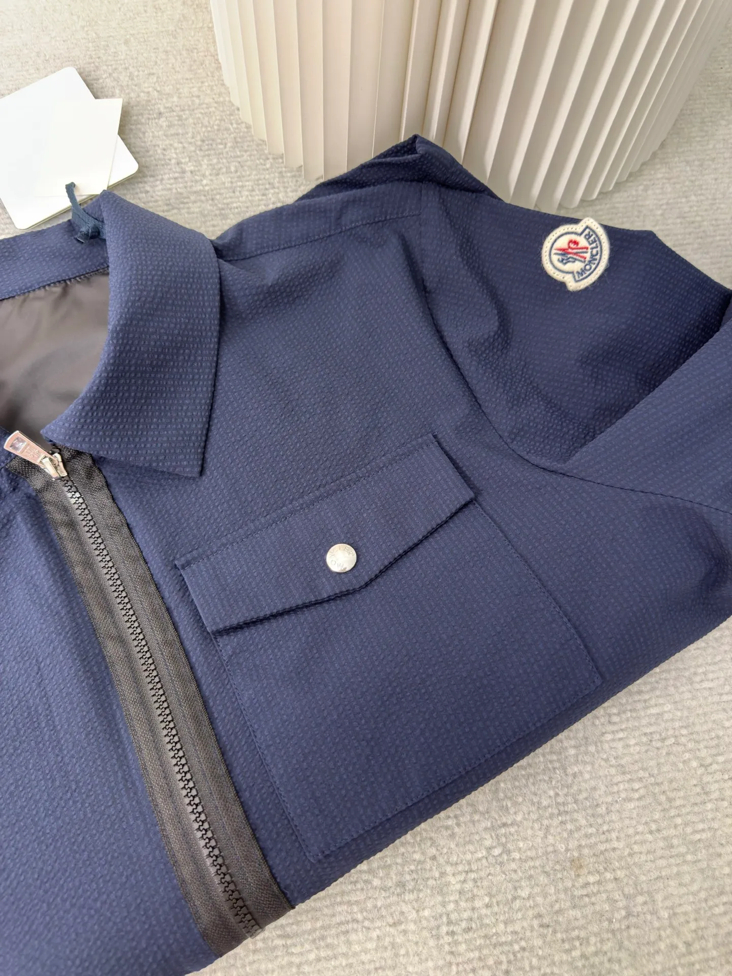P450 MONCLER Puff Wrinkle Shirt Jacket. Authentic version - physical counter - top luxury quality. 🆚Second price of all versions on the market. Made of cotton blended woven fabric with 76% high cotton content + 24% polyester fiber. The high cotton content ensures that the fabric is soft, skin-friendly, and has good breathability. The addition of a small amount of polyester fiber balances the wrinkle resistance and elasticity of the overall fabric and greatly reduces its shrinkage. After preshrinking, dimensional changes during washing are negligible. The fusion of the two makes the fabric combine anti-wrinkle, quick-drying, easy care and other characteristics without losing the advantages of good wearing experience and strong breathability.  The ground warp + bubble warp is independently let-off. The bubble warp yarn feeding speed is about 20% higher than the ground warp yarn feeding speed. During weaving, the bubble warp is relaxed and accumulated, forming a naturally arched bubble unit. Through the alternating arrangement of yarns and the change of floating tissue, a clear grid frame is built between the bubble units. Finally, the bubble three-dimensional effect and grid outline are locked through high-temperature heat setting. Size:1 2 3 4