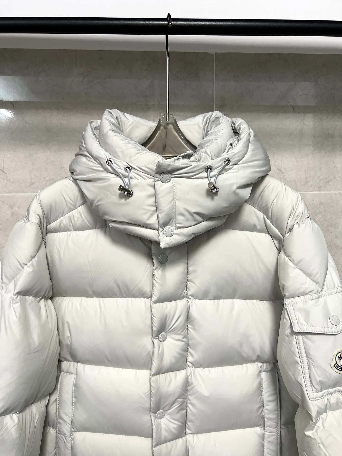 P800 Moncler matte Maya short down jacket. This short parka down jacket is made of longueSaion fabric. The garment is full of functional details to ensure warmth and care. Features removable hood, zip pockets, adjustable cuffs, and snap-zip flap fly. Logo embellished sleeves. It adds a unique touch to the overall shape and significantly improves the protective performance. Color: Black White Pink Pearl White Size: 12345