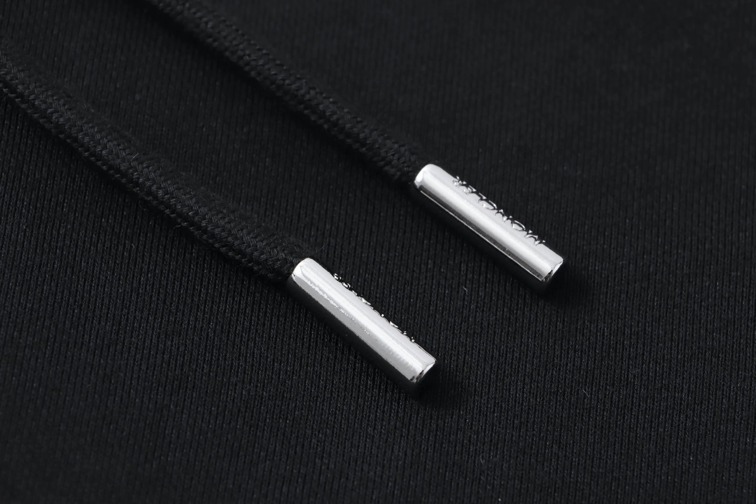 P340 Moncler slogan printed zipper hooded jacket is made of lightweight turned velvet cotton fabric. High-density cotton fiber is used to achieve internal and external differentiation in a single layer of fabric. The outer plain weave is tight and wear-resistant, and the inner layer is sanded to form a short dense suede surface. The dense plain weave structure resists wind and splashes, the brushed suede surface is skin-friendly, and the short pile has been treated to eliminate static electricity to avoid sticking to the skin. A very small amount of grooved polyester moisture-conducting yarn is embedded in the cotton fiber, which quickly guides sweat from the inner suede surface to the outer layer for evaporation through the capillary effect, solving the problem of the suede being easily stuffy. By actively interfering with the shrinkage potential of cotton fibers, the fabric is able to transition from changeable to stable, improving dimensional stability while being less prone to deformation and wrinkles. High saturation is achieved on the center of the cap through glue printing. Size: xs-l