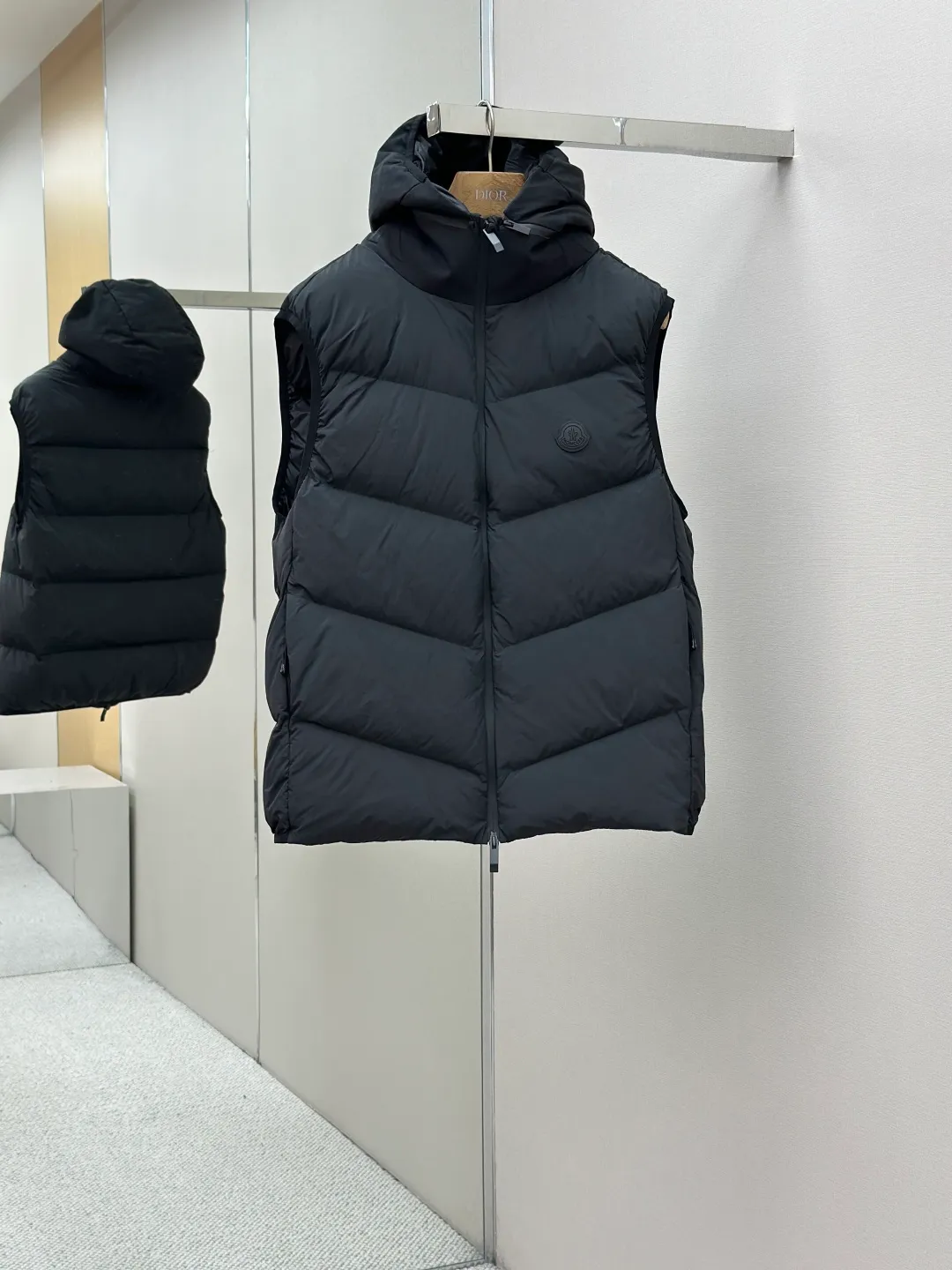 P660 MONCLER Badge Hooded Down Vest Fabric selection: Made of nylon fabric made of 100% nylon, which is woven into a tight and tough fabric through advanced textile technology. It improves the strength of the skeleton to effectively block the invasion of cold wind and lock the warm air generated by the down layer. After tight weaving and special treatment, it has waterproof and windproof functions. The surface forms a certain lotus leaf effect, and is wrinkle-resistant and not easily deformed, making it easy for daily care.  Technology: The quilting stitches are sewn in a diagonal direction at an angle of approximately 70 degrees. The diagonal lines are arranged in parallel. The fabric and filling are planned into different functional areas, and the quilting stitches in each partition are relatively independent. This allows the finished product to produce a larger deformation space along the diagonal direction when stretched and pressed, making it less likely to tighten and break, and has rich visual effects, modern and advanced features.  Details: After the hood is removed, the stand-up collar displays an embossed logo of the same color, adding a unique visual experience and tactile details.  High-quality filling: It is filled with 90% selected white duck down, weighing 170g, ensuring fluffy rebound, lightness and warmth.  Accessories: One-to-one customized zipper pendant, one-to-one customized badge, one-to-one customized three-label SIZE: 1 2 3 4