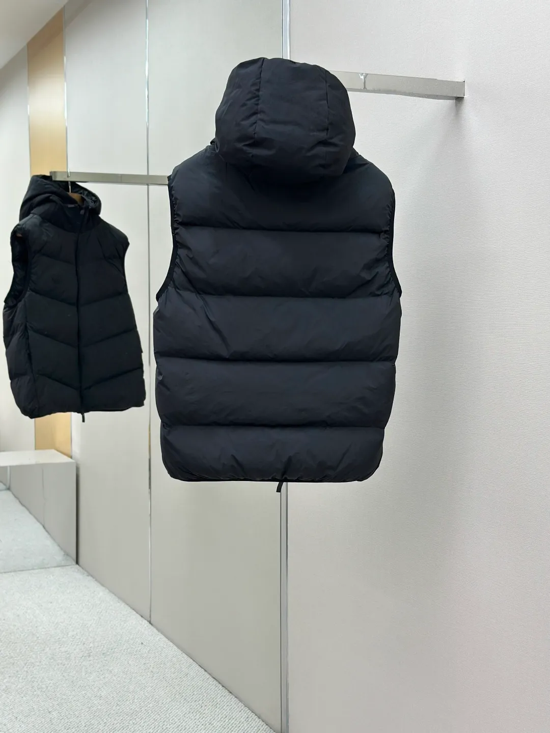 P660 MONCLER Badge Hooded Down Vest Fabric selection: Made of nylon fabric made of 100% nylon, which is woven into a tight and tough fabric through advanced textile technology. It improves the strength of the skeleton to effectively block the invasion of cold wind and lock the warm air generated by the down layer. After tight weaving and special treatment, it has waterproof and windproof functions. The surface forms a certain lotus leaf effect, and is wrinkle-resistant and not easily deformed, making it easy for daily care.  Technology: The quilting stitches are sewn in a diagonal direction at an angle of approximately 70 degrees. The diagonal lines are arranged in parallel. The fabric and filling are planned into different functional areas, and the quilting stitches in each partition are relatively independent. This allows the finished product to produce a larger deformation space along the diagonal direction when stretched and pressed, making it less likely to tighten and break, and has rich visual effects, modern and advanced features.  Details: After the hood is removed, the stand-up collar displays an embossed logo of the same color, adding a unique visual experience and tactile details.  High-quality filling: It is filled with 90% selected white duck down, weighing 170g, ensuring fluffy rebound, lightness and warmth.  Accessories: One-to-one customized zipper pendant, one-to-one customized badge, one-to-one customized three-label SIZE: 1 2 3 4
