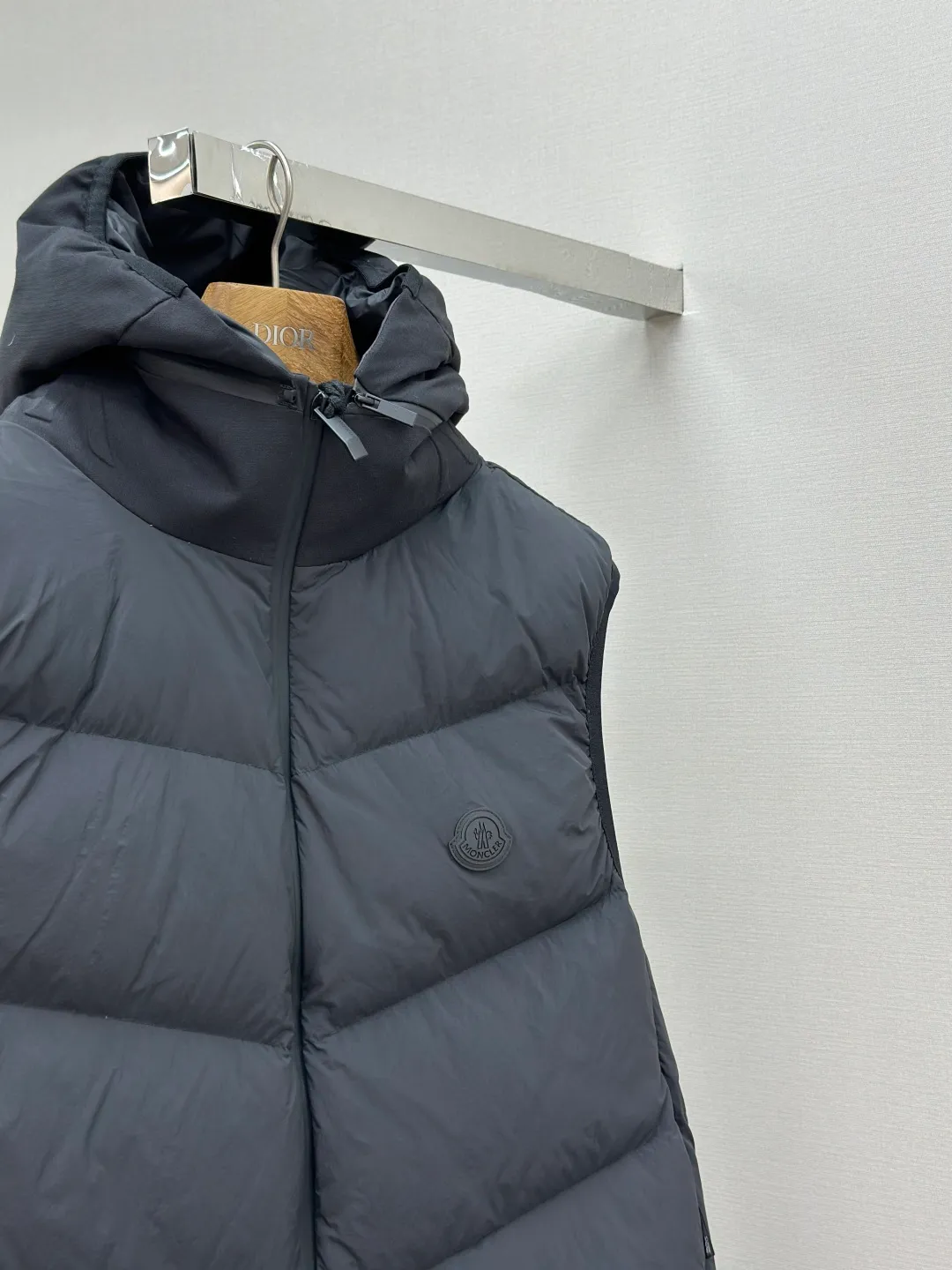 P660 MONCLER Badge Hooded Down Vest Fabric selection: Made of nylon fabric made of 100% nylon, which is woven into a tight and tough fabric through advanced textile technology. It improves the strength of the skeleton to effectively block the invasion of cold wind and lock the warm air generated by the down layer. After tight weaving and special treatment, it has waterproof and windproof functions. The surface forms a certain lotus leaf effect, and is wrinkle-resistant and not easily deformed, making it easy for daily care.  Technology: The quilting stitches are sewn in a diagonal direction at an angle of approximately 70 degrees. The diagonal lines are arranged in parallel. The fabric and filling are planned into different functional areas, and the quilting stitches in each partition are relatively independent. This allows the finished product to produce a larger deformation space along the diagonal direction when stretched and pressed, making it less likely to tighten and break, and has rich visual effects, modern and advanced features.  Details: After the hood is removed, the stand-up collar displays an embossed logo of the same color, adding a unique visual experience and tactile details.  High-quality filling: It is filled with 90% selected white duck down, weighing 170g, ensuring fluffy rebound, lightness and warmth.  Accessories: One-to-one customized zipper pendant, one-to-one customized badge, one-to-one customized three-label SIZE: 1 2 3 4