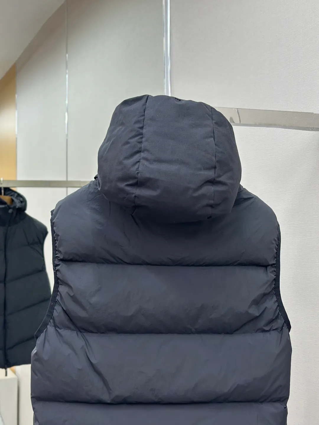 P660 MONCLER Badge Hooded Down Vest Fabric selection: Made of nylon fabric made of 100% nylon, which is woven into a tight and tough fabric through advanced textile technology. It improves the strength of the skeleton to effectively block the invasion of cold wind and lock the warm air generated by the down layer. After tight weaving and special treatment, it has waterproof and windproof functions. The surface forms a certain lotus leaf effect, and is wrinkle-resistant and not easily deformed, making it easy for daily care.  Technology: The quilting stitches are sewn in a diagonal direction at an angle of approximately 70 degrees. The diagonal lines are arranged in parallel. The fabric and filling are planned into different functional areas, and the quilting stitches in each partition are relatively independent. This allows the finished product to produce a larger deformation space along the diagonal direction when stretched and pressed, making it less likely to tighten and break, and has rich visual effects, modern and advanced features.  Details: After the hood is removed, the stand-up collar displays an embossed logo of the same color, adding a unique visual experience and tactile details.  High-quality filling: It is filled with 90% selected white duck down, weighing 170g, ensuring fluffy rebound, lightness and warmth.  Accessories: One-to-one customized zipper pendant, one-to-one customized badge, one-to-one customized three-label SIZE: 1 2 3 4