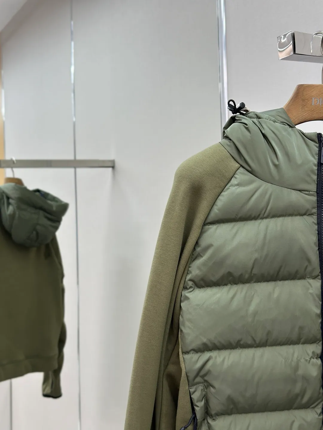 P810 Moncler logo woven splicing down jacket, customized matte crystal lattice air shield velvet and 300D high-density calendered coating, using the new national standard 90 white duck down (welcome to test), full of down, full of warmth, light and fluffy, with the dark green of the overlapping mountains as the background color, all things accumulating, creating its own scenery in silence The Monlcer triangle logo is embellished on the chest, the power aesthetics of the minimalist logo The concentrated down filling in the front area creates dynamic insulation for the core heat dissipation zone of the human body. The hooded down is a moving warm flow barrier for the head and neck, forming a thermal energy circulation system with the front area. The elastic woven sleeves provide freedom of movement with a sense of compression, forming a relaxed and warm philosophy. The real high-end is to let function become the footnote of style. Process 1: Computer mechanical down filling. Prioritize the liner pattern by making a pattern to determine the down filling area and determine the weight of down per square meter according to the original three-dimensional effect. Thus, the amount of down filling for each cut piece is calculated. The computer down filling machine uses a digital weighing unit to achieve stable measurement. Process 2: 3D three-dimensional quilting technology. With the programming system of the CNC quilting machine, the down in different areas is accurately separated to ensure that the filling is evenly fixed after sewing and avoid agglomeration or displacement. Process 3: Computer template machine line running process. The computer template machine line line process shows extremely high neatness and smoothness. The craftsman's precise control of the size during the operation ensures that each line meets the design requirements. The lines of the entire template are smooth and unified, neat and beautiful. Process 4: Triple locking five-thread dense stitching process. Main seam locking + diagonal reinforcement + raw edge wrapping. Triple structure. Forming a three-dimensional protective net at the edge of the fabric to avoid stitch breakage. Paving materials: Customized Moncler zippers. Customized Moncler rope loops. Customized Moncler logo. Customized Moncler eyelets. Customized Moncler trademark. Size: S M L XL