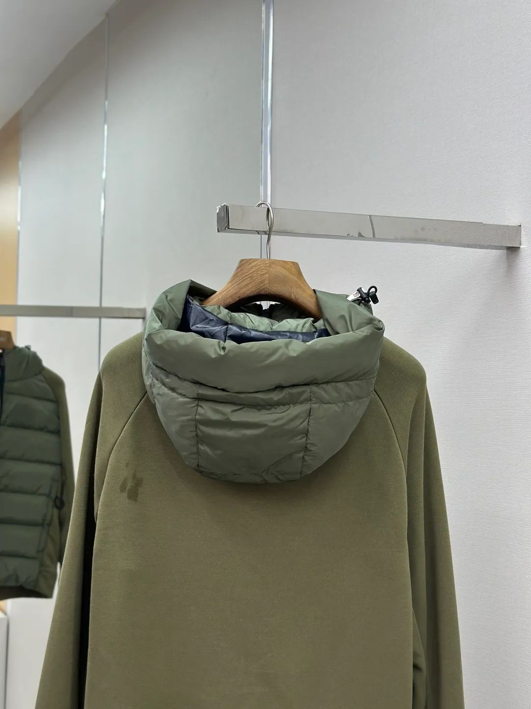 P810 Moncler logo woven splicing down jacket, customized matte crystal lattice air shield velvet and 300D high-density calendered coating, using the new national standard 90 white duck down (welcome to test), full of down, full of warmth, light and fluffy, with the dark green of the overlapping mountains as the background color, all things accumulating, creating its own scenery in silence The Monlcer triangle logo is embellished on the chest, the power aesthetics of the minimalist logo The concentrated down filling in the front area creates dynamic insulation for the core heat dissipation zone of the human body. The hooded down is a moving warm flow barrier for the head and neck, forming a thermal energy circulation system with the front area. The elastic woven sleeves provide freedom of movement with a sense of compression, forming a relaxed and warm philosophy. The real high-end is to let function become the footnote of style. Process 1: Computer mechanical down filling. Prioritize the liner pattern by making a pattern to determine the down filling area and determine the weight of down per square meter according to the original three-dimensional effect. Thus, the amount of down filling for each cut piece is calculated. The computer down filling machine uses a digital weighing unit to achieve stable measurement. Process 2: 3D three-dimensional quilting technology. With the programming system of the CNC quilting machine, the down in different areas is accurately separated to ensure that the filling is evenly fixed after sewing and avoid agglomeration or displacement. Process 3: Computer template machine line running process. The computer template machine line line process shows extremely high neatness and smoothness. The craftsman's precise control of the size during the operation ensures that each line meets the design requirements. The lines of the entire template are smooth and unified, neat and beautiful. Process 4: Triple locking five-thread dense stitching process. Main seam locking + diagonal reinforcement + raw edge wrapping. Triple structure. Forming a three-dimensional protective net at the edge of the fabric to avoid stitch breakage. Paving materials: Customized Moncler zippers. Customized Moncler rope loops. Customized Moncler logo. Customized Moncler eyelets. Customized Moncler trademark. Size: S M L XL