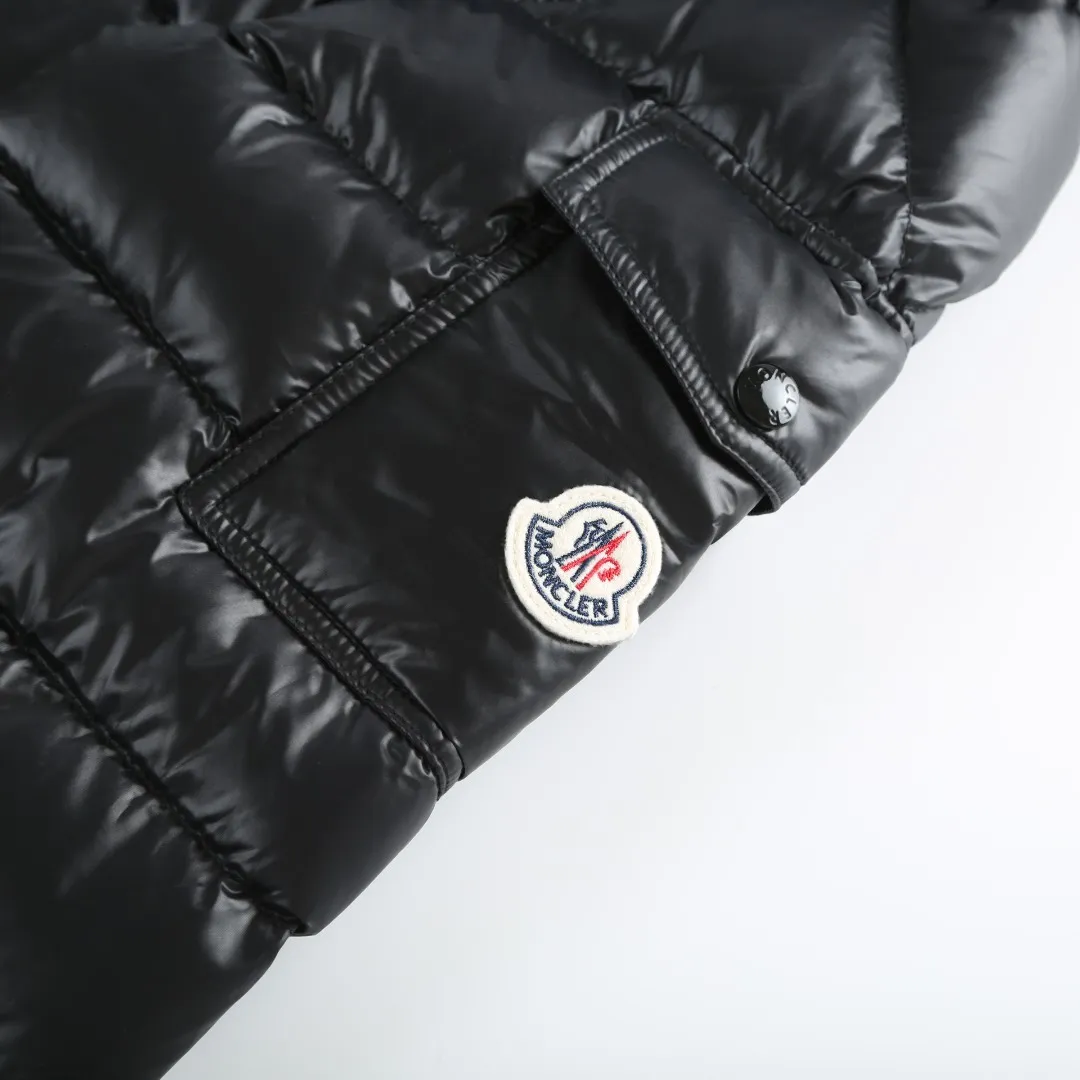 P900 MONCLER hooded brim quilted embroidered down jacket Fabric selection: The longue saison fabric is made of high-count polyamide fiber, which is known for its excellent tensile strength and lightness. Its good flexibility makes the fabric less prone to wrinkles and keeps it crisp and stylish for a long time. The tight weave effectively blocks the invasion of cold wind and locks in the warm air generated by the down layer. The high-density nylon surface forms a certain lotus leaf effect, making it difficult for small water droplets to penetrate, keeping the interior dry and effectively extending the service life of the down.  Lining selection: High-density lining fabric made of ultra-fine denier, 0.08mm thickness to avoid increasing the overall weight and making it smooth to wear. The high-density woven structure forms a wind resistance layer to protect the thermal efficiency of the thermal layer from loss. It can also withstand the expansion pressure of down and prevent deformation and damage after long-term use.  Technology: The quilted letter logo on the brim uses contour quilting technology. The stitching is routed along the edge of the set outline, and the filler is compressed inside the letter graphic, so that the logo is three-dimensional and convex, and the pattern is clear.  High-quality filling: It is filled with 90% selected white duck down, weighing 210g, ensuring fluffy rebound, lightness and warmth.  Accessories: one-to-one customized zipper pendant, one-to-one customized badge, one-to-one customized three-label SIZE: 1 2 3 4