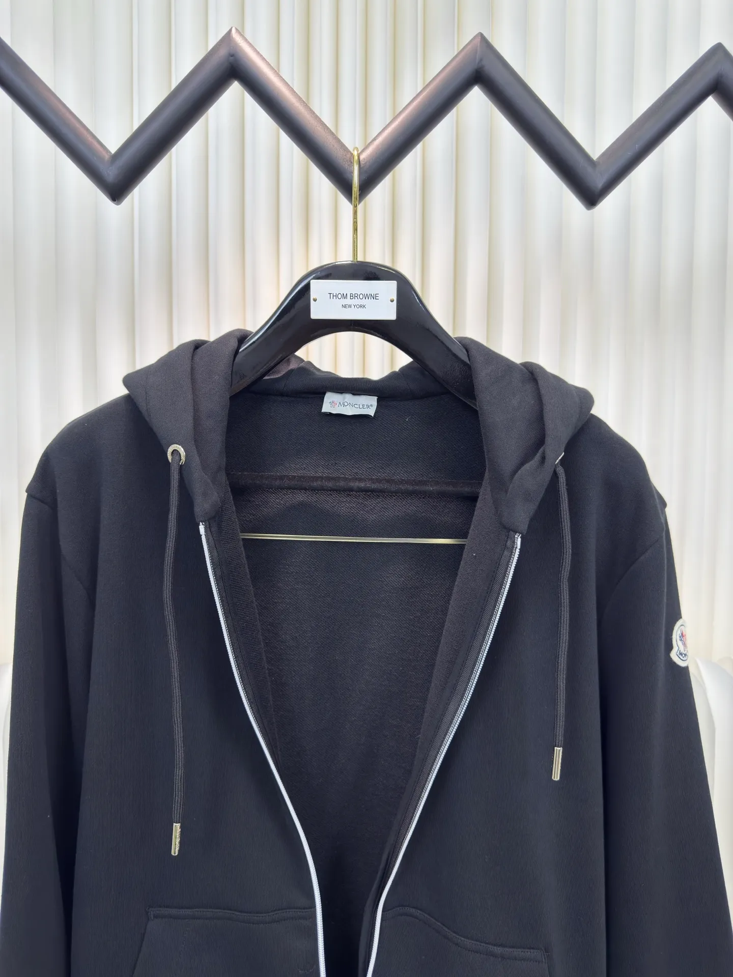 P500 MONCLER printed logo hooded sweatshirt is made of lightweight turned-over velvet cotton fabric. High-density cotton fiber is used to achieve internal and external differentiation in a single layer of fabric. The outer plain weave is tight and wear-resistant, and the inner layer is sanded to form a short dense suede surface. The dense plain weave structure resists wind and splashes, the brushed suede surface is skin-friendly, and the short pile has been treated to eliminate static electricity to avoid sticking to the skin. A very small amount of grooved polyester moisture-conducting yarn is embedded in the cotton fiber, which quickly directs sweat from the inner suede surface to the outer layer for evaporation through the capillary effect, solving the problem that the inside-out suede is prone to stuffiness. By actively intervening in the shrinkage potential of the cotton fiber, the fabric is achieved from being volatile to stable, improving dimensional stability, and at the same time not prone to deformation and wrinkles.   A high-saturation pattern is displayed on the center of the cap through glue printing. The scraper pressure is even and the scraping is performed in 5 steps to ensure that the glue is fully penetrated and covered. After curing at high temperature, the pigment is firmly combined with the cotton fiber. The ink absorption and penetration characteristics of the cotton fiber make the pattern less likely to fall off due to friction. Size S M L XL