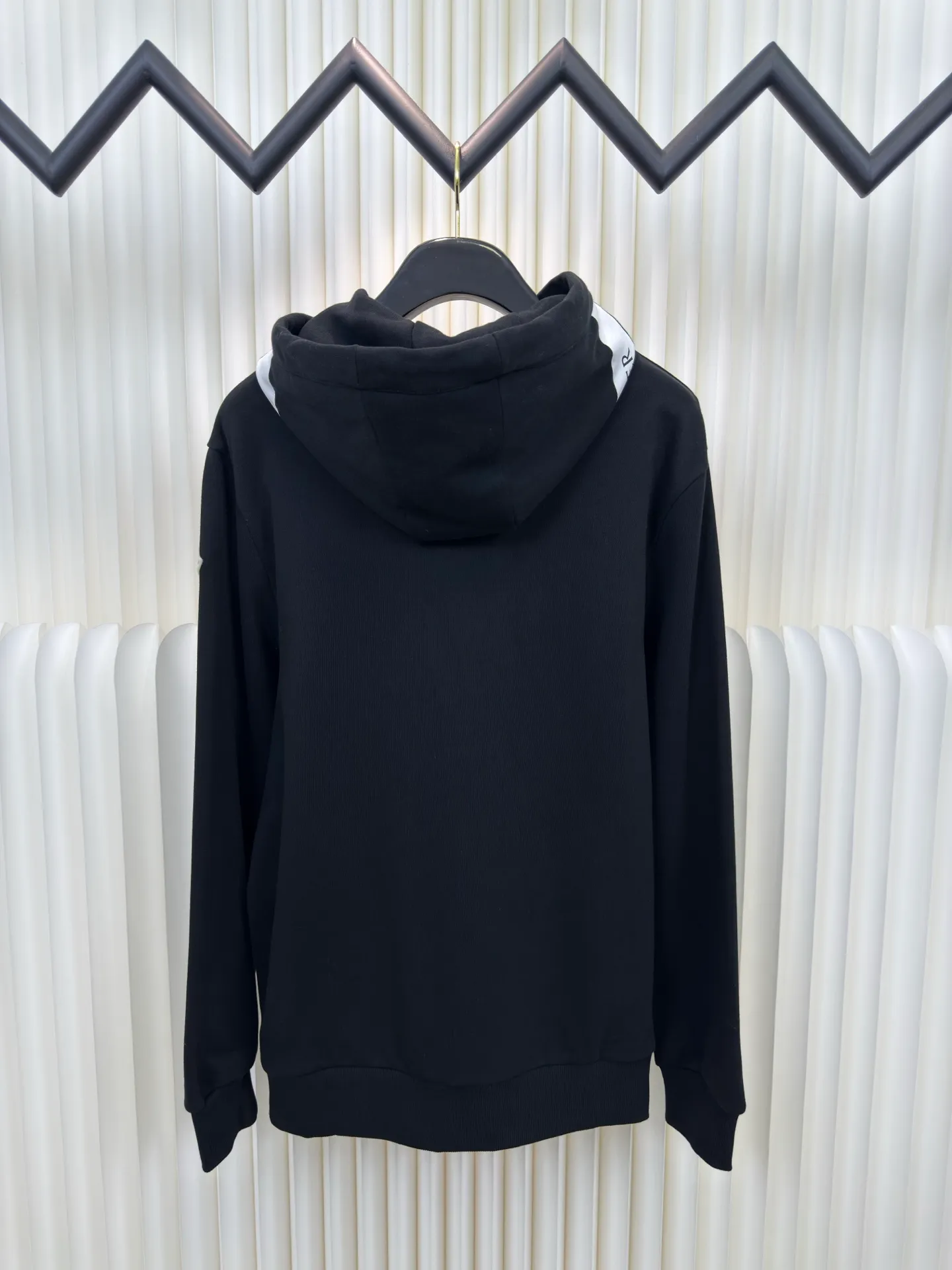 P500 MONCLER printed logo hooded sweatshirt is made of lightweight turned-over velvet cotton fabric. High-density cotton fiber is used to achieve internal and external differentiation in a single layer of fabric. The outer plain weave is tight and wear-resistant, and the inner layer is sanded to form a short dense suede surface. The dense plain weave structure resists wind and splashes, the brushed suede surface is skin-friendly, and the short pile has been treated to eliminate static electricity to avoid sticking to the skin. A very small amount of grooved polyester moisture-conducting yarn is embedded in the cotton fiber, which quickly directs sweat from the inner suede surface to the outer layer for evaporation through the capillary effect, solving the problem that the inside-out suede is prone to stuffiness. By actively intervening in the shrinkage potential of the cotton fiber, the fabric is achieved from being volatile to stable, improving dimensional stability, and at the same time not prone to deformation and wrinkles.   A high-saturation pattern is displayed on the center of the cap through glue printing. The scraper pressure is even and the scraping is performed in 5 steps to ensure that the glue is fully penetrated and covered. After curing at high temperature, the pigment is firmly combined with the cotton fiber. The ink absorption and penetration characteristics of the cotton fiber make the pattern less likely to fall off due to friction. Size S M L XL