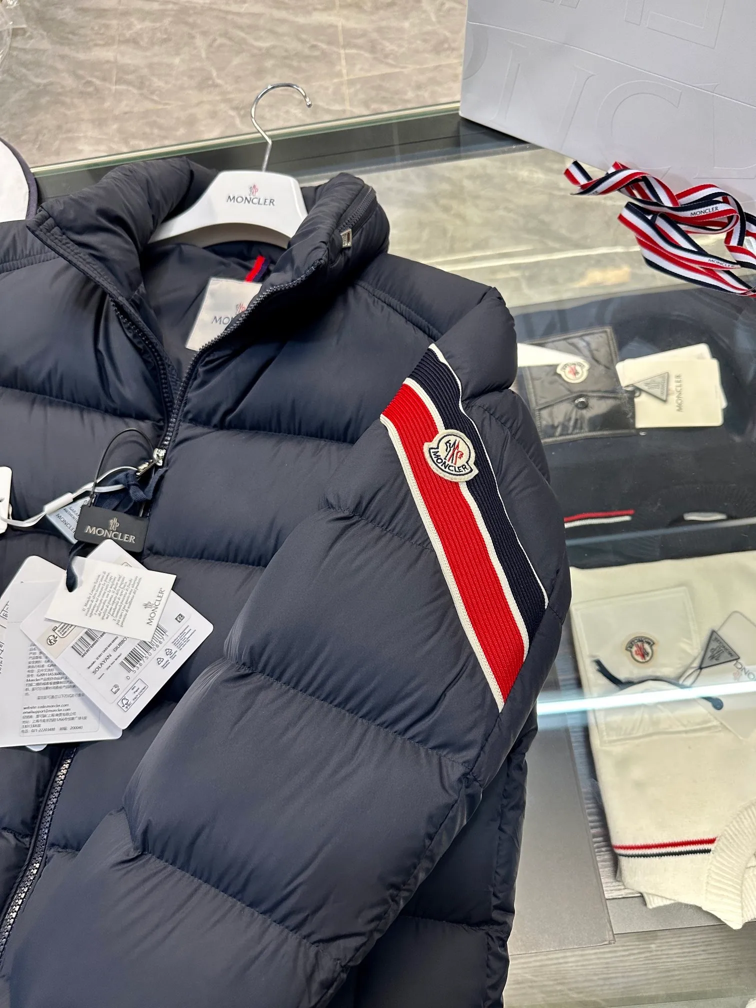 P920 2024N haute couture down moncler solayan men's three-color trimmed short down. Premium goose down filling. The most delicate, lightest and neatest fabric. Solayan men's short down is decorated with seasonal iconic stripe details, blending sportsmanship and timeless style. Solayan down is made of micro chic fabric and has a tough square shape design, highlighting Moncler's sporty spirit. This cropped style has tricolor stripes on the sleeves, a seasonal take on the brand's signature. Comes with a practical pull-out hood. Details · Made of micro chic nylon fabric · Micro chic nylon lining · Filled down · Pull-out hood · Zipper closure · Zipper pocket · Adjustable cuffs · Elastic drawstring hem · Tri-color trim on sleeves size: 1-5 Color: white, dark brown, black