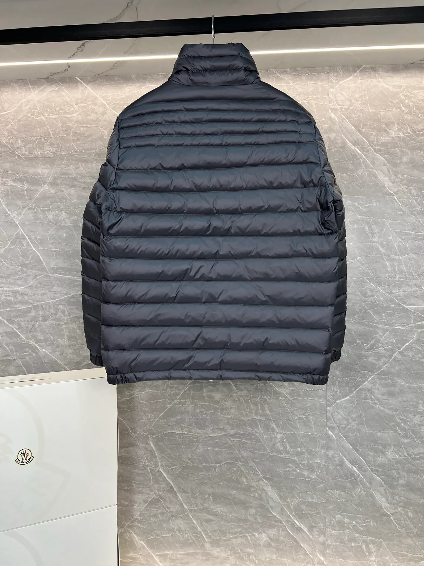 P780 Moncler Arnique short and lightweight men's down jacket. Super soft and delicate fabric, white duck down filling. Extremely lightweight and warm. The Arnique hooded down jacket is made of polyester fiber outer fabric and is Moncler's classic men's design item.  The Arnique short down jacket features classic checkered quilting and signature patch pockets on the sleeves, highlighting the Moncler style. The outer fabric reflects the brand's commitment to lowering its environmental footprint. Modular design, removable hood can be easily put on and taken off according to weather conditions. Details Made of polyester outer fabric Polyester lining Filled with down Size: 1-5 Silver Gray Black