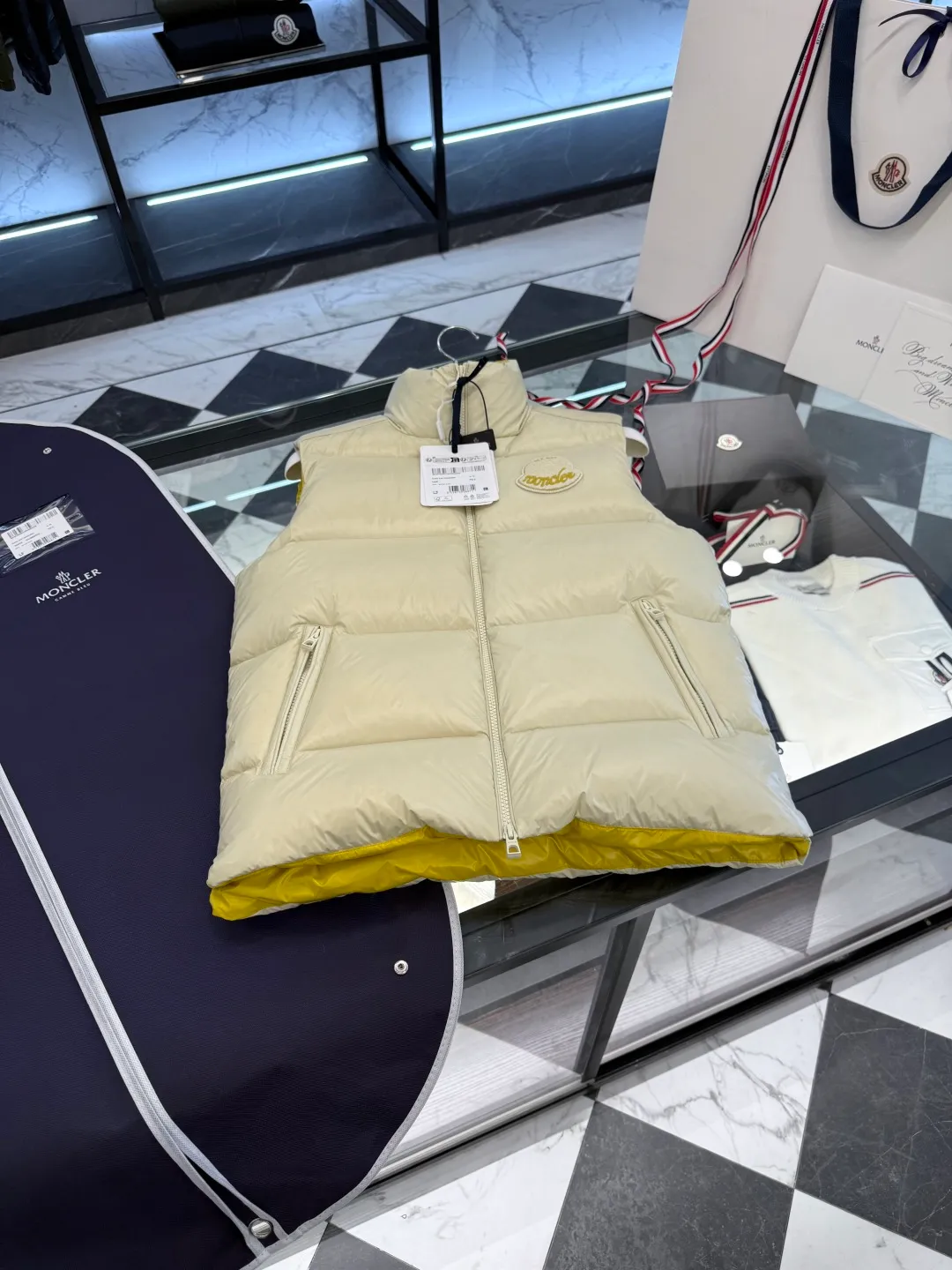 P660 Moncler Lipsi down vest. Contrast color splicing design. Super full filling. Lipsi men's down vest is made of shiny nylon laqué fabric, suitable for wearing in different seasons, bringing warmth and care.  The Lipsi short down vest embodies Moncler's classic design and is a must-have item for your wardrobe from season to season. Crafted from lightweight, functional nylon laqué fabric, it has a contrast lining for a vibrant feel. Details •Made from lightweight nylon laqué fabric •Lightweight nylon laqué lining •Filled with down •Stand-up collar •Zipper closure •Zip pockets •Chenille logo patch Size: 1-5 Black/Ivory Couple Style
