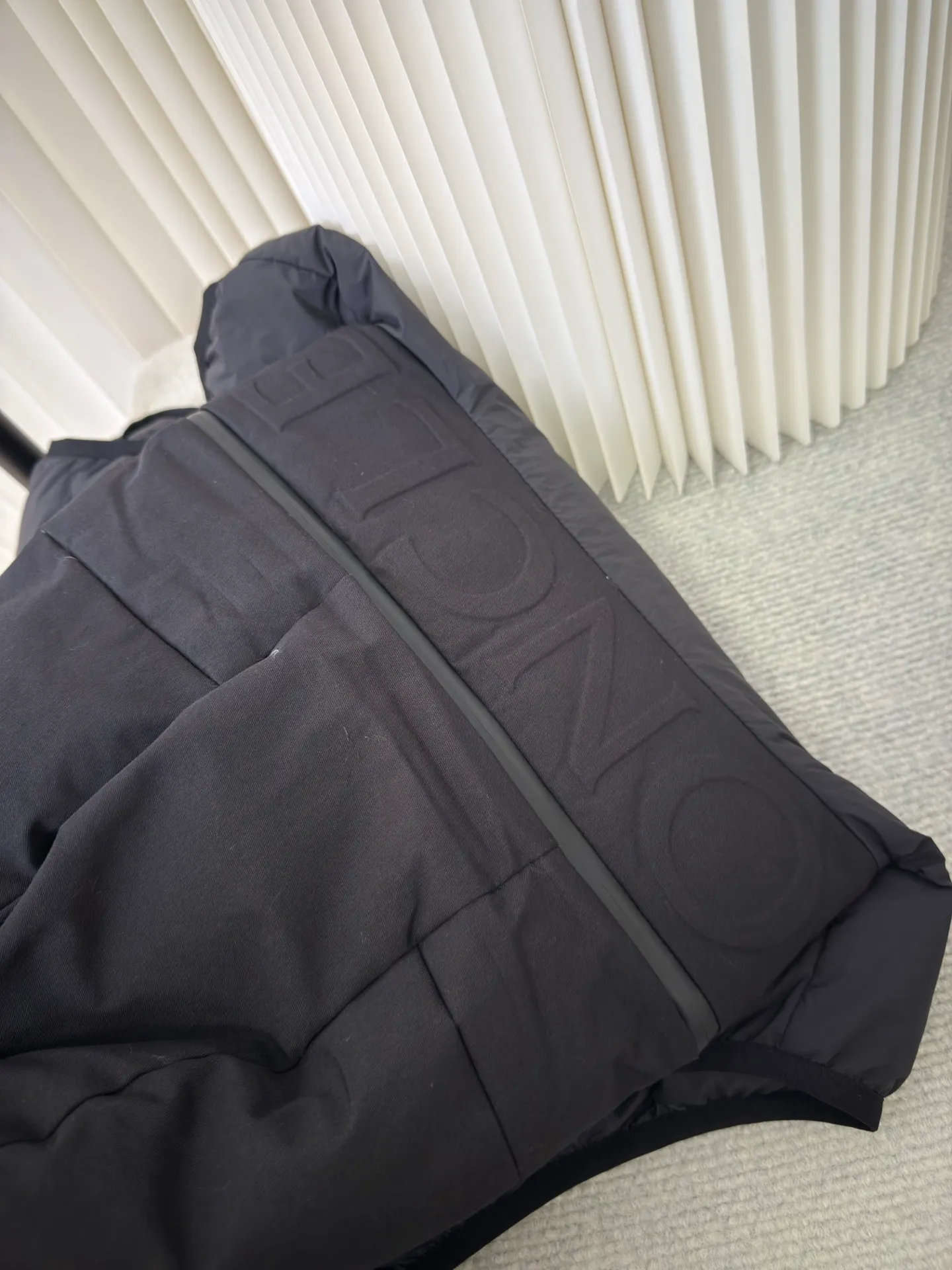P660 MONCLER Badge Hooded Down Vest is made of nylon fabric made of 100% nylon. It is woven into a tight and tough fabric through advanced textile technology. It improves the strength of the frame and effectively blocks the invasion of cold wind and locks in the warm air generated by the down layer. After tight weaving and special treatment, it is waterproof and windproof. The surface forms a certain lotus leaf effect. It is also wrinkle-resistant and not easy to deform, making it easy for daily care.  The quilting stitches are sewn in a diagonal direction at an angle of about 70 degrees, and the diagonal lines are arranged in parallel. The fabric and filling are planned into different functional areas, and the quilting stitches in each partition are relatively independent. This allows the finished product to produce a larger deformation space along the diagonal direction when stretched and pressed, making it less likely to tighten and break, and has rich visual effects, modern and advanced features.  After the hood is removed, the stand-up collar displays an embossed logo of the same color, adding a unique visual experience and tactile details. High-quality filling: It is filled with 90% selected white duck down, weighing 170g, ensuring fluffy rebound, lightness and warmth. Size 1 2 3 4