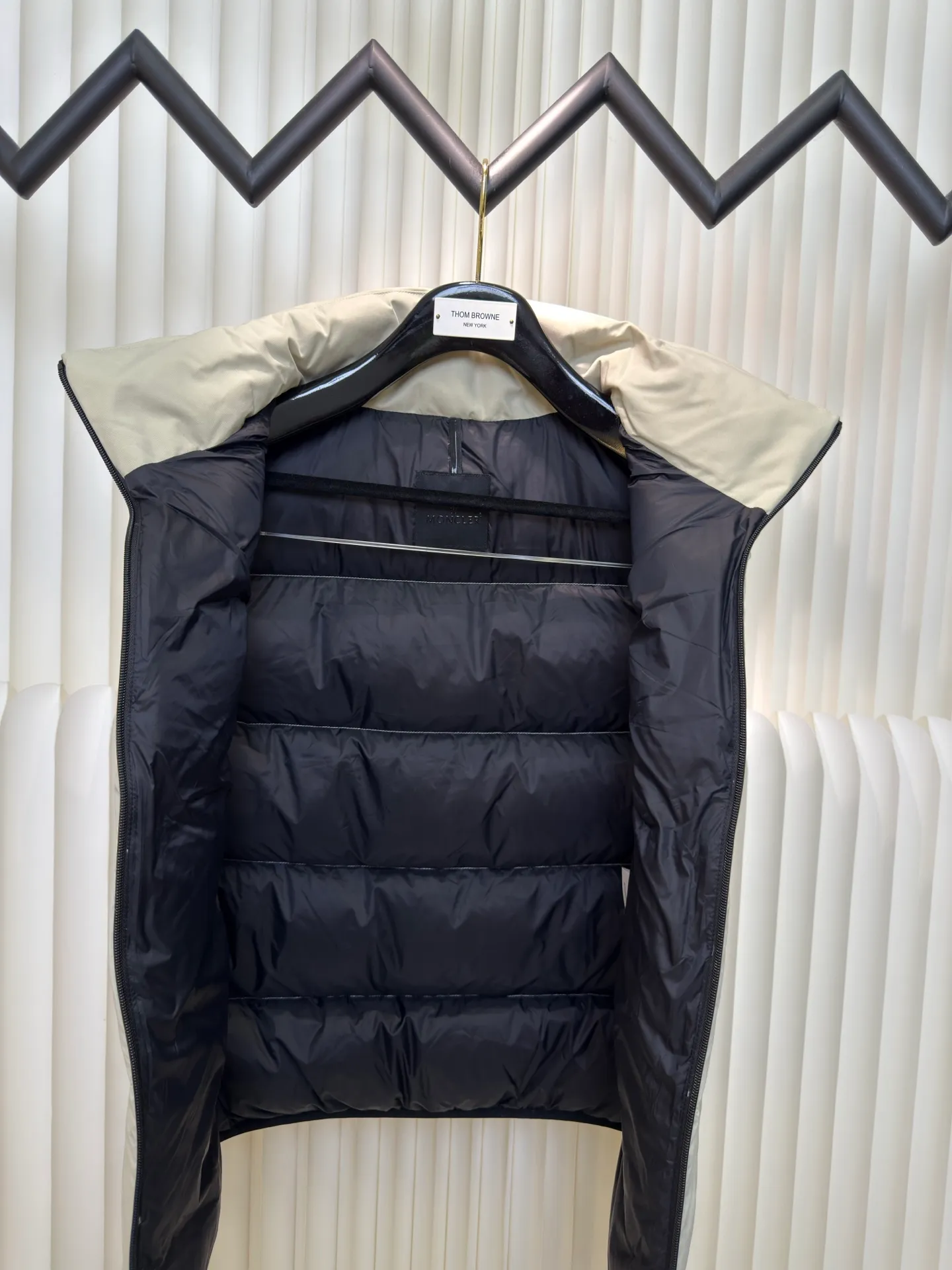 P660 MONCLER Badge Hooded Down Vest is made of nylon fabric made of 100% nylon. It is woven into a tight and tough fabric through advanced textile technology. It improves the strength of the frame and effectively blocks the invasion of cold wind and locks in the warm air generated by the down layer. After tight weaving and special treatment, it is waterproof and windproof. The surface forms a certain lotus leaf effect. It is also wrinkle-resistant and not easy to deform, making it easy for daily care.  The quilting stitches are sewn in a diagonal direction at an angle of about 70 degrees, and the diagonal lines are arranged in parallel. The fabric and filling are planned into different functional areas, and the quilting stitches in each partition are relatively independent. This allows the finished product to produce a larger deformation space along the diagonal direction when stretched and pressed, making it less likely to tighten and break, and has rich visual effects, modern and advanced features.  After the hood is removed, the stand-up collar displays an embossed logo of the same color, adding a unique visual experience and tactile details. High-quality filling: It is filled with 90% selected white duck down, weighing 170g, ensuring fluffy rebound, lightness and warmth. Size 1 2 3 4