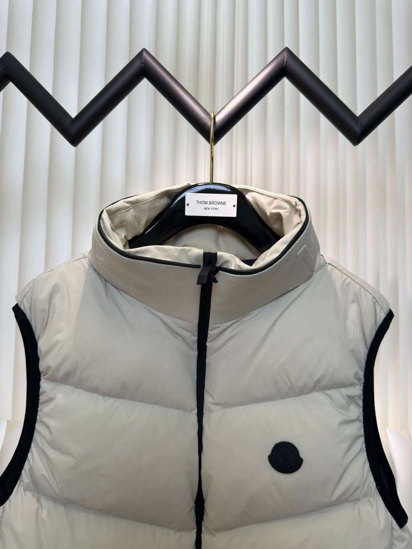 P660 MONCLER Badge Hooded Down Vest is made of nylon fabric made of 100% nylon. It is woven into a tight and tough fabric through advanced textile technology. It improves the strength of the frame and effectively blocks the invasion of cold wind and locks in the warm air generated by the down layer. After tight weaving and special treatment, it is waterproof and windproof. The surface forms a certain lotus leaf effect. It is also wrinkle-resistant and not easy to deform, making it easy for daily care.  The quilting stitches are sewn in a diagonal direction at an angle of about 70 degrees, and the diagonal lines are arranged in parallel. The fabric and filling are planned into different functional areas, and the quilting stitches in each partition are relatively independent. This allows the finished product to produce a larger deformation space along the diagonal direction when stretched and pressed, making it less likely to tighten and break, and has rich visual effects, modern and advanced features.  After the hood is removed, the stand-up collar displays an embossed logo of the same color, adding a unique visual experience and tactile details. High-quality filling: It is filled with 90% selected white duck down, weighing 170g, ensuring fluffy rebound, lightness and warmth. Size 1 2 3 4