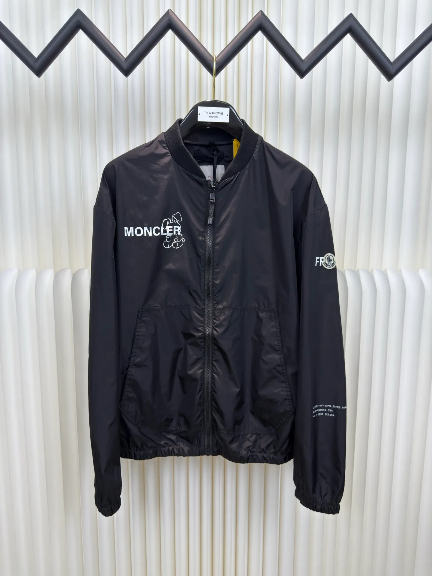 P530 Moncler Hiroshi Fujiwara co-branded bomber jacket is a coated nylon canvas fabric formed after nylon base material and coating treatment. The coating can effectively block moisture penetration, making it very waterproof. The nylon itself has high wear resistance. The ribbed knitted cotton collar and the cool luster of the coated nylon form a visual and physical contrast. The cotton ribbing is warm and skin-friendly, durable and not easily deformed after being washed. The zipper opens and closes, and a strap is attached to the zipper head to make it easier to open and close clothing. There are patch pockets on the left and right sides, and the edges of the pockets are reinforced with double-needle sewing technology, which is strong and beautiful at the same time. The cuffs and hem are closed with flat ribs to ensure no binding, ensuring wind resistance and warmth, and not easily deformed.  Screen glue printing. During the printing process of glue printing, the glue will form a thick colloid layer, making the printed pattern have a three-dimensional effect. It not only enhances the visual effect of printing, but also makes the hand feel richer. After the glue printing is cured, the printed pattern is closely integrated with the fabric and is not easy to fall off or wear. Size: 1 2 3 4
