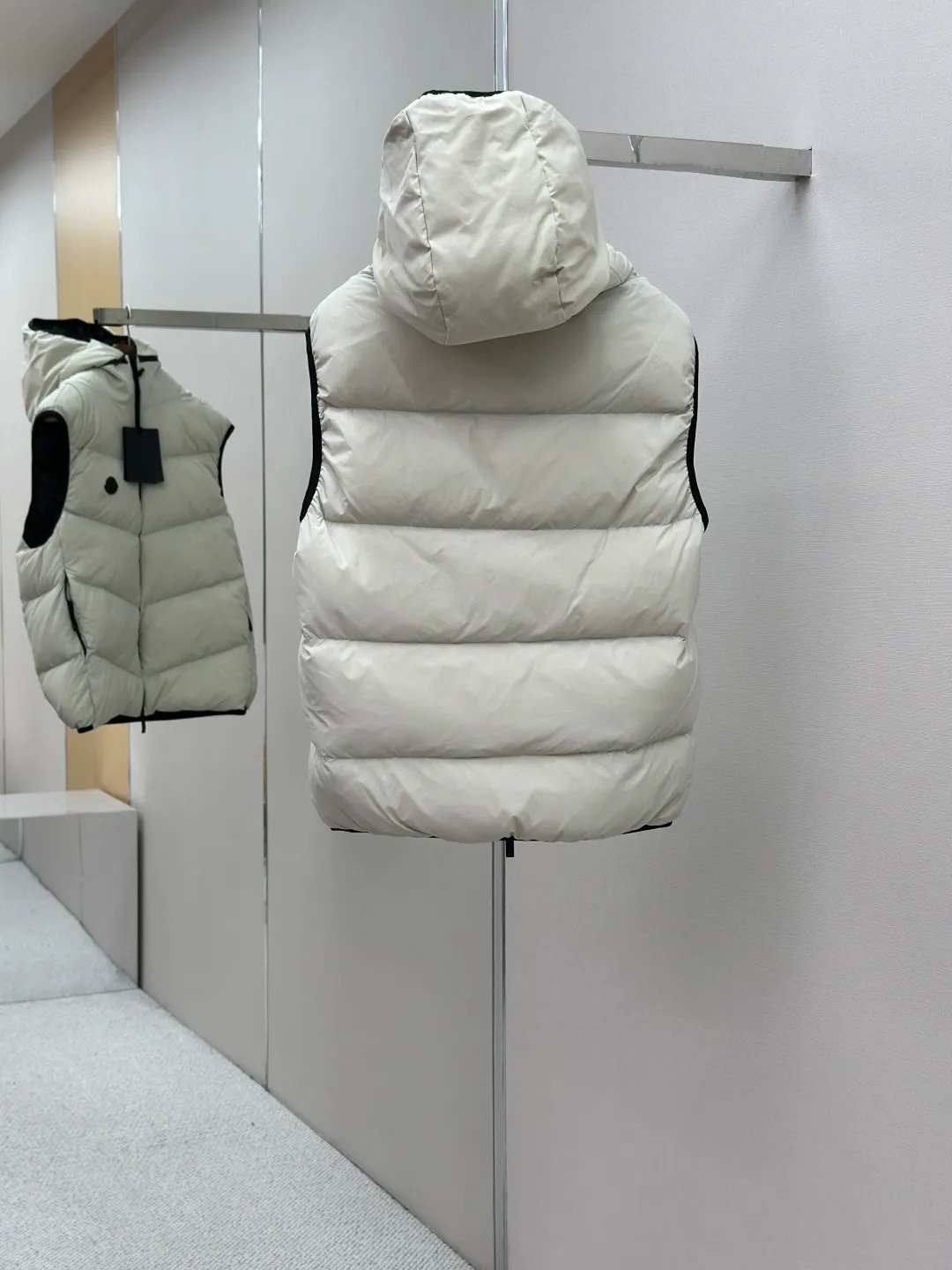 P660 MONCLER Badge Hooded Down Vest Fabric selection: Made of nylon fabric made of 100% nylon, which is woven into a tight and tough fabric through advanced textile technology. It improves the strength of the skeleton to effectively block the invasion of cold wind and lock the warm air generated by the down layer. After tight weaving and special treatment, it has waterproof and windproof functions. The surface forms a certain lotus leaf effect, and is wrinkle-resistant and not easily deformed, making it easy for daily care.  Technology: The quilting stitches are sewn in a diagonal direction at an angle of approximately 70 degrees. The diagonal lines are arranged in parallel. The fabric and filling are planned into different functional areas, and the quilting stitches in each partition are relatively independent. This allows the finished product to produce a larger deformation space along the diagonal direction when stretched and pressed, making it less likely to tighten and break, and has rich visual effects, modern and advanced features.  Details: After the hood is removed, the stand-up collar displays an embossed logo of the same color, adding a unique visual experience and tactile details.  High-quality filling: It is filled with 90% selected white duck down, weighing 170g, ensuring fluffy rebound, lightness and warmth.  Accessories: One-to-one customized zipper pendant, one-to-one customized badge, one-to-one customized three-label SIZE: 1 2 3 4