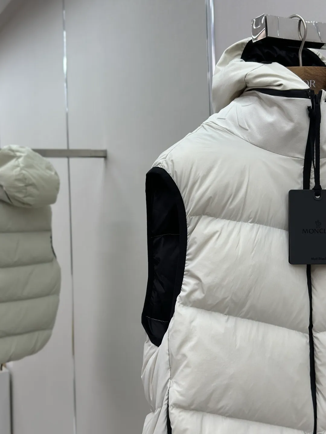 P660 MONCLER Badge Hooded Down Vest Fabric selection: Made of nylon fabric made of 100% nylon, which is woven into a tight and tough fabric through advanced textile technology. It improves the strength of the skeleton to effectively block the invasion of cold wind and lock the warm air generated by the down layer. After tight weaving and special treatment, it has waterproof and windproof functions. The surface forms a certain lotus leaf effect, and is wrinkle-resistant and not easily deformed, making it easy for daily care.  Technology: The quilting stitches are sewn in a diagonal direction at an angle of approximately 70 degrees. The diagonal lines are arranged in parallel. The fabric and filling are planned into different functional areas, and the quilting stitches in each partition are relatively independent. This allows the finished product to produce a larger deformation space along the diagonal direction when stretched and pressed, making it less likely to tighten and break, and has rich visual effects, modern and advanced features.  Details: After the hood is removed, the stand-up collar displays an embossed logo of the same color, adding a unique visual experience and tactile details.  High-quality filling: It is filled with 90% selected white duck down, weighing 170g, ensuring fluffy rebound, lightness and warmth.  Accessories: One-to-one customized zipper pendant, one-to-one customized badge, one-to-one customized three-label SIZE: 1 2 3 4