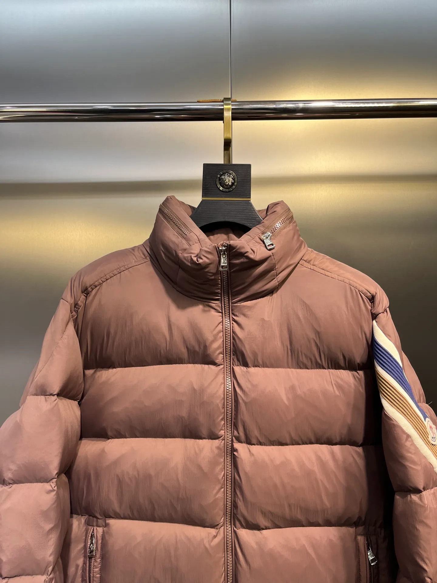 P840 Moncler Solayan men's tri-color trim short down jacket. Filled with premium goose down. The finest, lightest and neatest fabric. Solayan men's short down jacket is decorated with the season's signature stripe details, blending sporty spirit with timeless style. The Solayan down jacket is made of micro chic fabric and has a tough square shape design, highlighting Moncler's sporty spirit. This cropped down jacket features tricolor stripes on the sleeves, a seasonal take on the brand's signature. Comes with a practical pull-out hood. Details •Made from micro chic nylon fabric •Micro chic nylon lining •Down filled •Pull-out hood •Zip closure •Zip pockets •Adjustable cuffs •Elastic drawstring hem •Tri-color trim on sleeves Size: 1-5 Color: White Dark Brown Black
