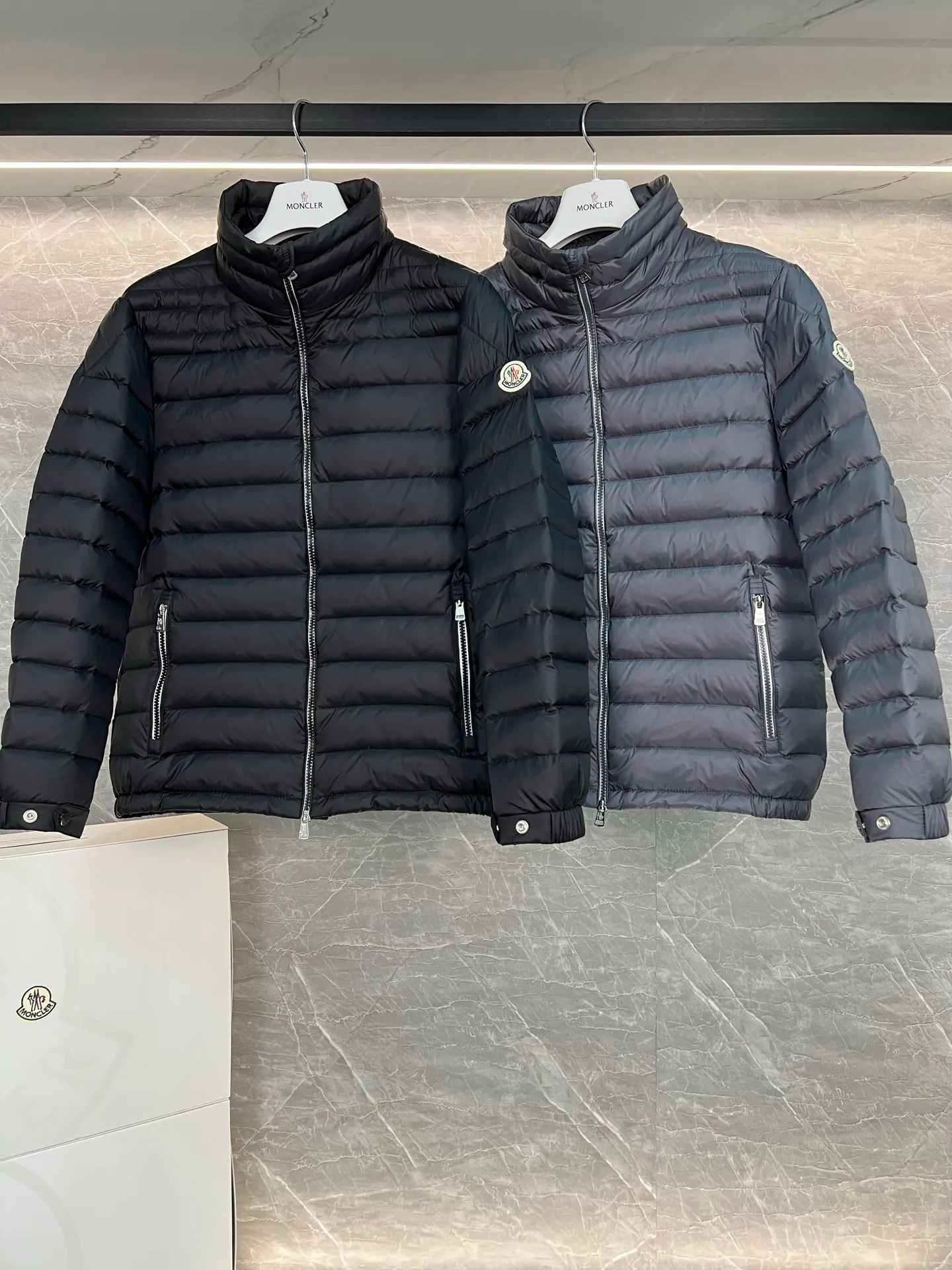 P780 Moncler Arnique short and lightweight men's down jacket. Super soft and delicate fabric, white duck down filling. Extremely lightweight and warm. The Arnique hooded down jacket is made of polyester fiber outer fabric and is Moncler's classic men's design item.  The Arnique short down jacket features classic checkered quilting and signature patch pockets on the sleeves, highlighting the Moncler style. The outer fabric reflects the brand's commitment to lowering its environmental footprint. Modular design, removable hood can be easily put on and taken off according to weather conditions. Details Made of polyester outer fabric Polyester lining Filled with down Size: 1-5 Silver Gray Black