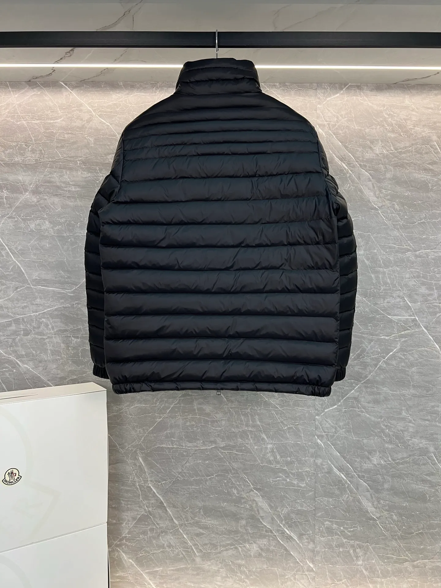 P780 Moncler Arnique short and lightweight men's down jacket. Super soft and delicate fabric, white duck down filling. Extremely lightweight and warm. The Arnique hooded down jacket is made of polyester fiber outer fabric and is Moncler's classic men's design item.  The Arnique short down jacket features classic checkered quilting and signature patch pockets on the sleeves, highlighting the Moncler style. The outer fabric reflects the brand's commitment to lowering its environmental footprint. Modular design, removable hood can be easily put on and taken off according to weather conditions. Details Made of polyester outer fabric Polyester lining Filled with down Size: 1-5 Silver Gray Black