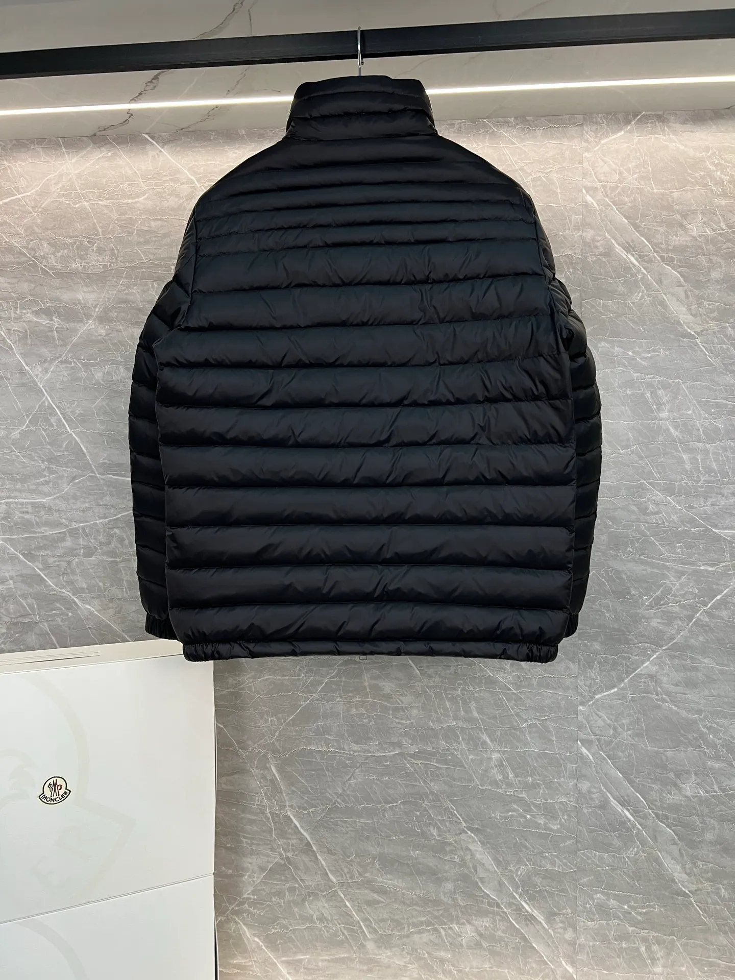 P780 Moncler Arnique short and lightweight men's down jacket. Super soft and delicate fabric, white duck down filling. Extremely lightweight and warm. The Arnique hooded down jacket is made of polyester fiber outer fabric and is Moncler's classic men's design item.  The Arnique short down jacket features classic checkered quilting and signature patch pockets on the sleeves, highlighting the Moncler style. The outer fabric reflects the brand's commitment to lowering its environmental footprint. Modular design, removable hood can be easily put on and taken off according to weather conditions. Details Made of polyester outer fabric Polyester lining Filled with down Size: 1-5 Silver Gray Black