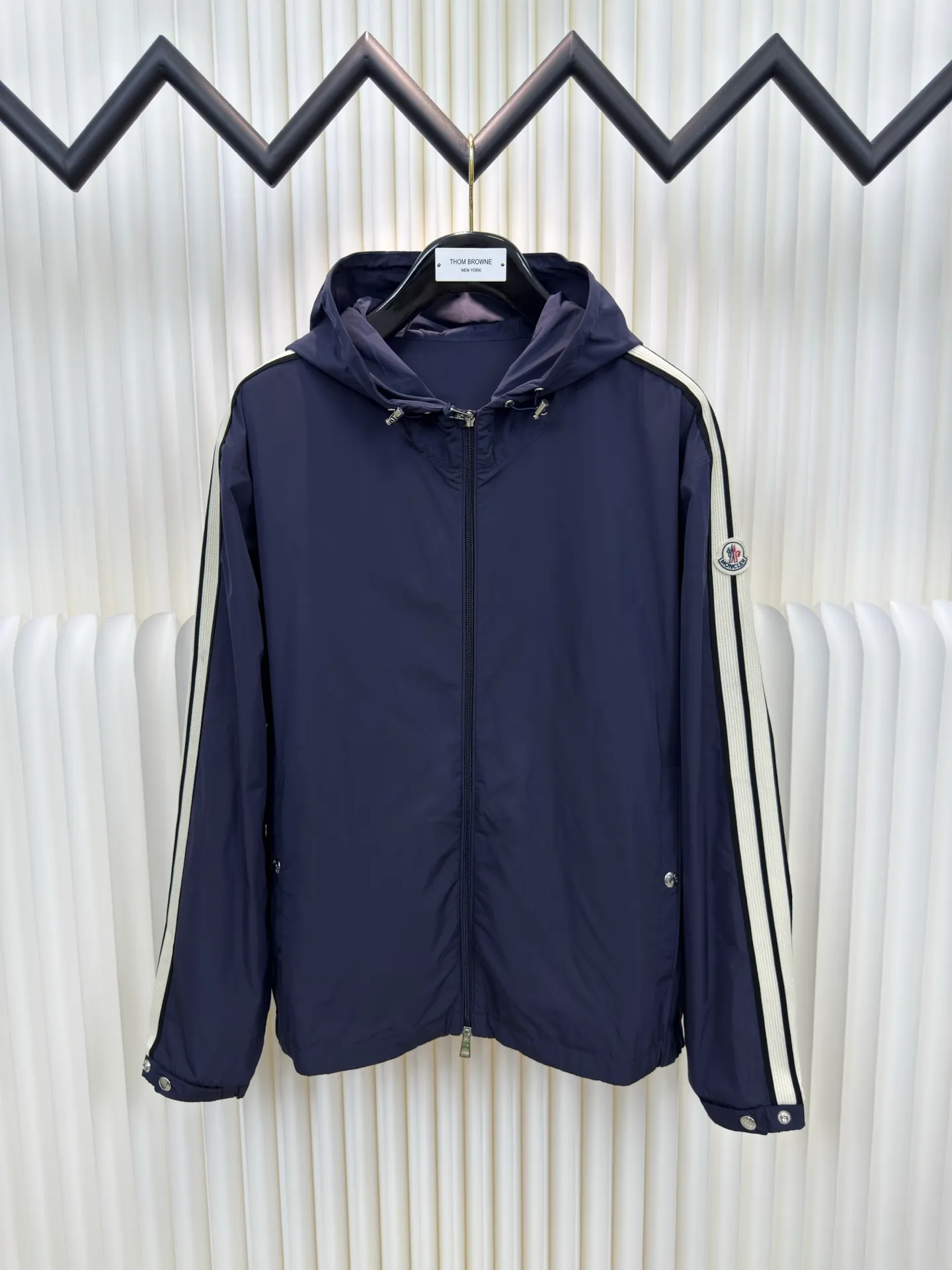 P570 MONCLER lightweight jacket with web trim at the mouth is made of 100% polyester fiber to create a tough protective outer layer. It is famous for its excellent tear resistance and wear resistance. It can quickly return to flatness during wearing and maintain the crisp and stylish appearance of the clothing for a long time. At the same time, it is not easy to deform after being washed for a long time.  Decorative edging in two different colors has been added to the center section of the sleeves. This design element not only adds visual highlights to clothing, making it more fashionable and unique. The webbing is precisely positioned along the cuffs to the seam of the collar and hat to ensure symmetry and overall smoothness. Before actual sewing, use very fine basting stitches for pre-fixing. This step is crucial to prevent the webbing from slipping, twisting, or wrinkling during sewing and ensuring that the final stitch is straight and perfect. Size 1 2 3 4