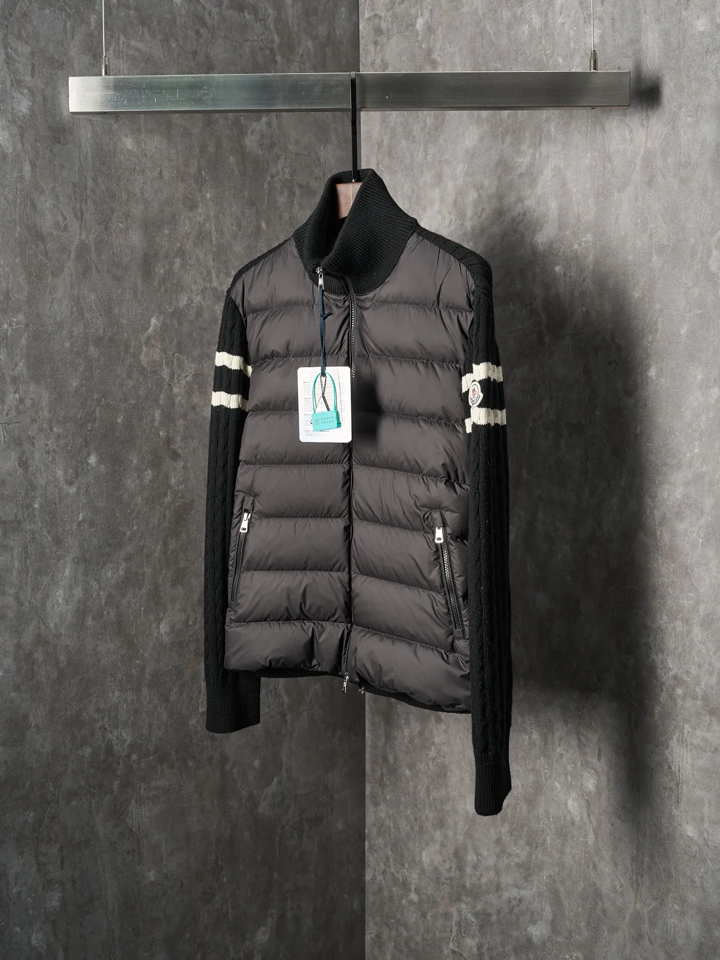 P780 Actual auction] Moncler/Mask Black classic stand-up collar spliced ​​wool knitted parallel bars armband zipper down jacket [Ready stock] S/1 M/2 L/3 XL/4 The outer front fabric is made of 100% nylon (nylon). Its high-density structure achieves excellent windproof effect. It also has strong wear resistance and wrinkle resistance. It is scratch-free for daily wear and easy to take care of.  The splicing design of sweaters and down jackets not only retains the thermal performance of down jackets, but also incorporates the fashion elements of sweaters, making the overall garment both practical and fashionable.  High-quality material: filled with high-quality white duck down, with a filling capacity of 100g, which has excellent thermal insulation effect. At the same time, the sweater is made of wool, cashmere and other natural fibers, which are soft, comfortable and skin-friendly.  The sweaters and down jackets are carefully spliced ​​to ensure comfortable wearing and are not prone to threading or velvet loss.  High collar design: not only provides excellent thermal insulation effect, but also adds a unique sense of fashion, allowing the wearer to maintain style in the cold season.  Stripe decoration: The stripes on the sleeve arms are like bright brush strokes, embellished on the dark gray down jacket, injecting vitality and movement into the overall look, making the clothing more eye-catching.