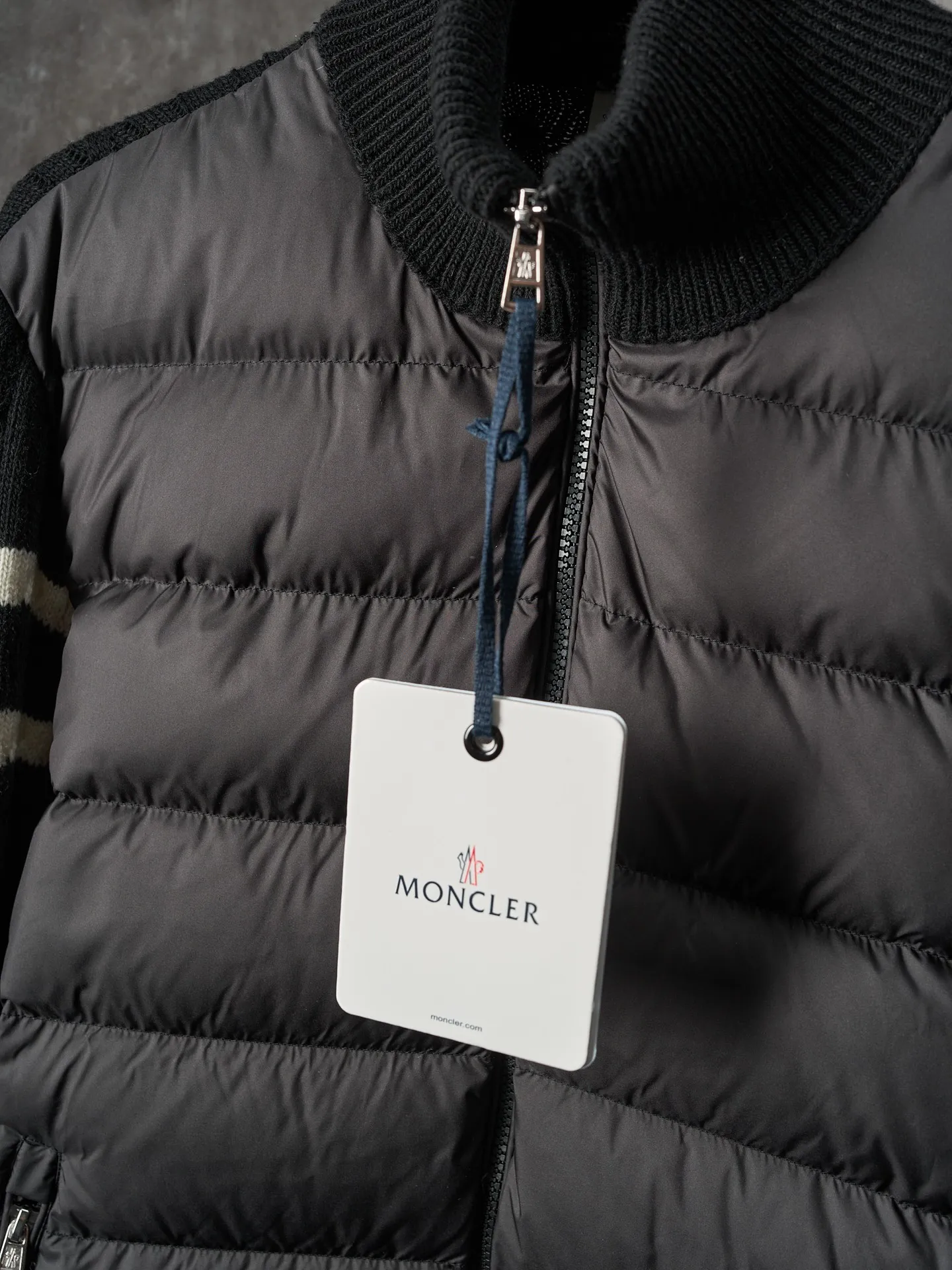 P780 Actual auction] Moncler/Mask Black classic stand-up collar spliced ​​wool knitted parallel bars armband zipper down jacket [Ready stock] S/1 M/2 L/3 XL/4 The outer front fabric is made of 100% nylon (nylon). Its high-density structure achieves excellent windproof effect. It also has strong wear resistance and wrinkle resistance. It is scratch-free for daily wear and easy to take care of.  The splicing design of sweaters and down jackets not only retains the thermal performance of down jackets, but also incorporates the fashion elements of sweaters, making the overall garment both practical and fashionable.  High-quality material: filled with high-quality white duck down, with a filling capacity of 100g, which has excellent thermal insulation effect. At the same time, the sweater is made of wool, cashmere and other natural fibers, which are soft, comfortable and skin-friendly.  The sweaters and down jackets are carefully spliced ​​to ensure comfortable wearing and are not prone to threading or velvet loss.  High collar design: not only provides excellent thermal insulation effect, but also adds a unique sense of fashion, allowing the wearer to maintain style in the cold season.  Stripe decoration: The stripes on the sleeve arms are like bright brush strokes, embellished on the dark gray down jacket, injecting vitality and movement into the overall look, making the clothing more eye-catching.