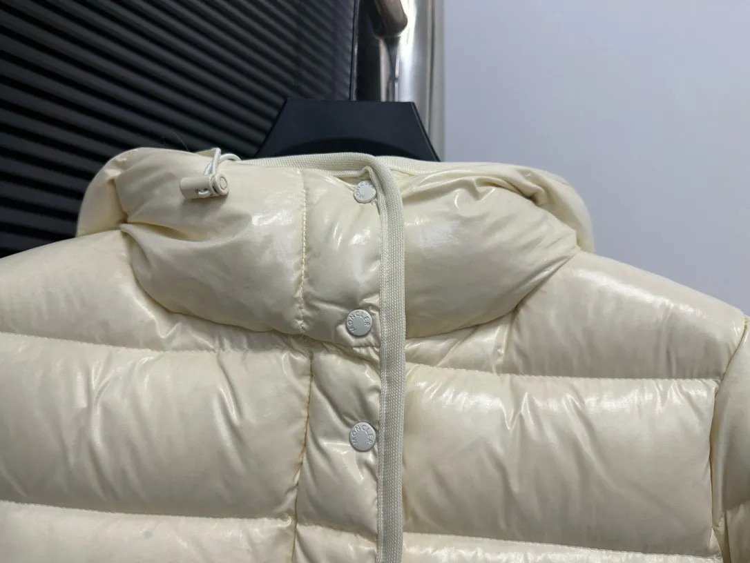 P860 [Moncler] Hooded, waisted women's short down jacket. The barante down jacket is made of glossy nylon fabric and is inspired by the 1970s. It adopts a waist design and presents an A-line silhouette, highlighting a feminine style. An adjustable hood and signature logo patch add finishing touches. Details · Made of lon laqué fabric · lon laqué lining · Filled with down · Adjustable hood · Zipper and snap closure · Suit pocket · Adjustable cuffs Size: 0/1/2/3